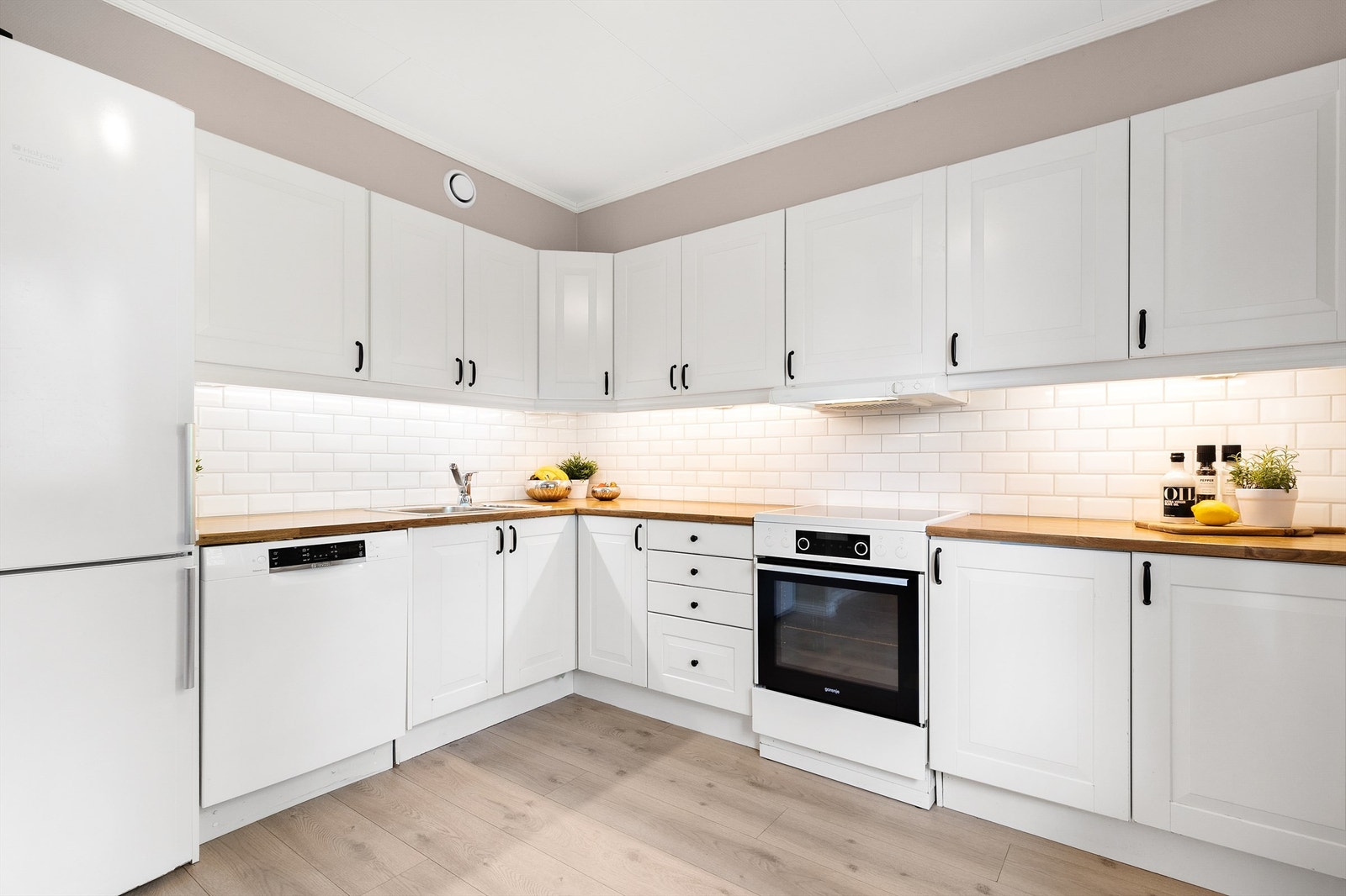 Åpen kjøkkenløsning med profilerte fronter fra byggeår i 2009. Det ble bygget håndtak og monter nye fliser mellom benkeplate og overskap i 2024. Galleribilde