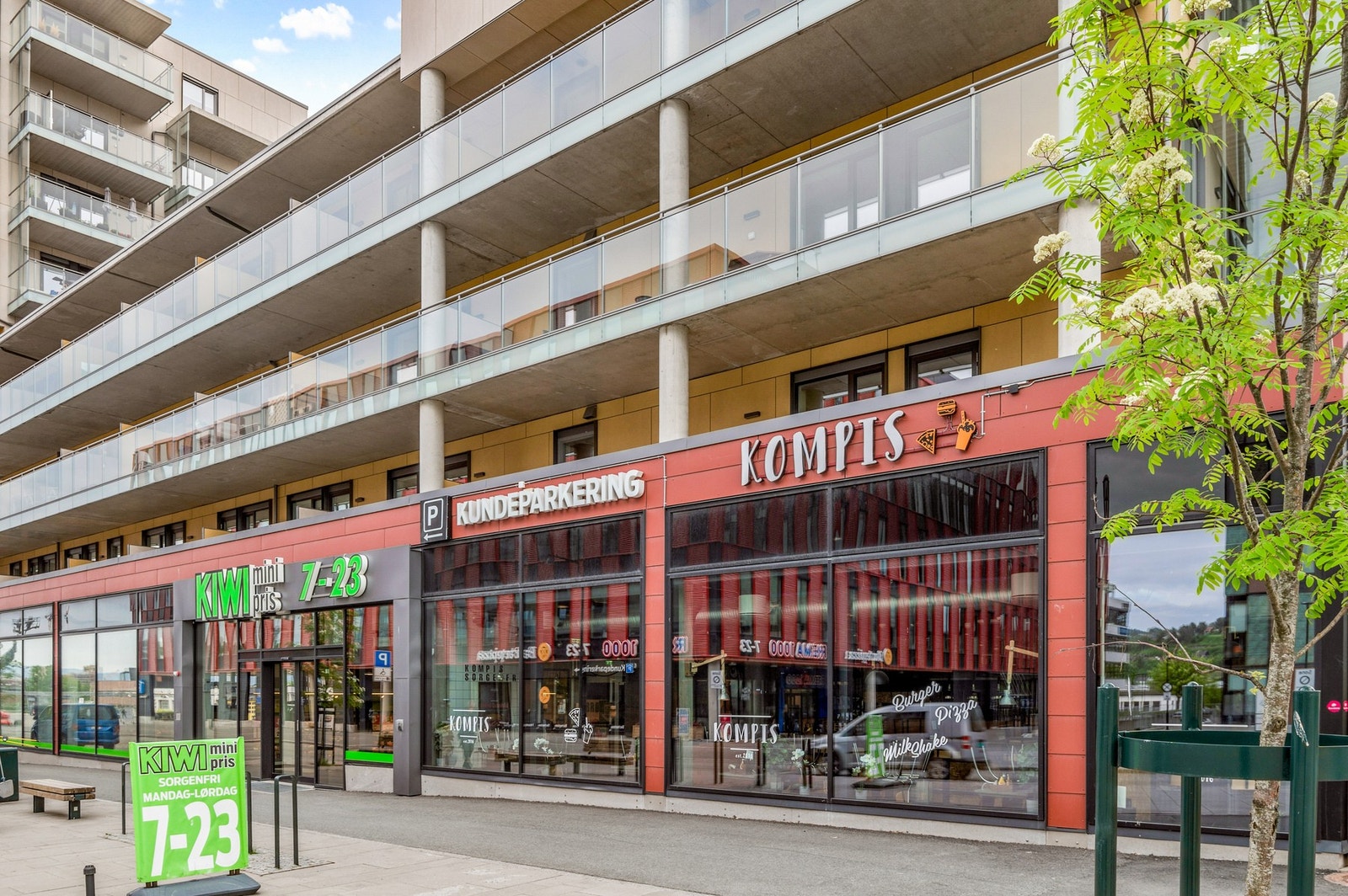 Kiwibutikk, Kompis restaurant og frisørsalong under leilighetene, på den andre sida av gata ligger en Remabutikk. Galleribilde