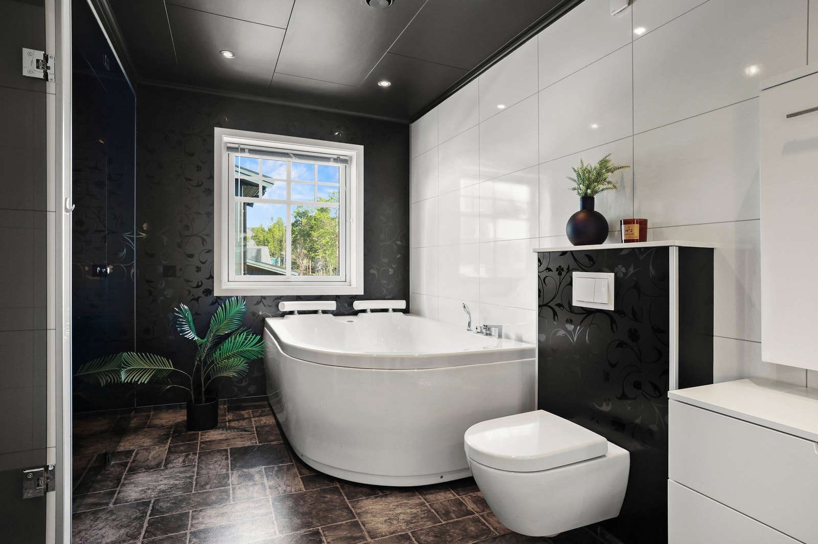 Badet inneholder vegghengt servantinnredning og speilskap med sidelys, badekar, dusj, badstue og vegghengt toalett. Galleribilde