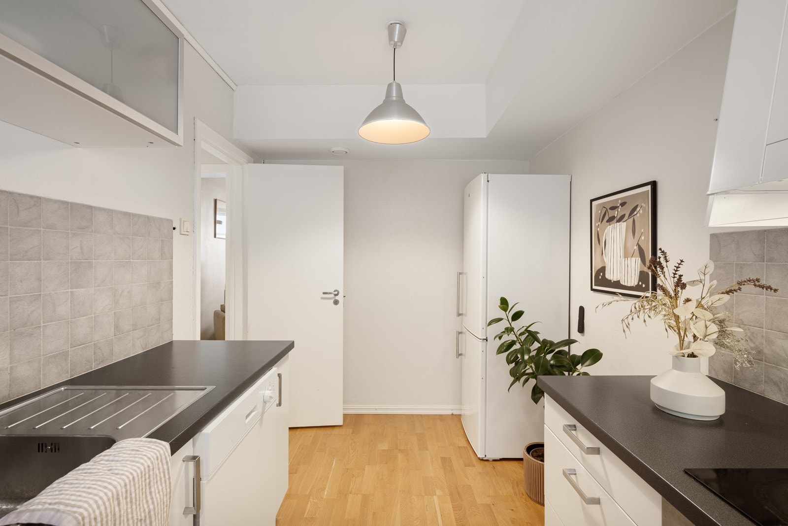 Ikea-innredningen fra 2011 har hvite, glatte fronter, overskap med frostede fronter og mørk benkeplate av laminat med nedfelt oppvaskkum. Galleribilde