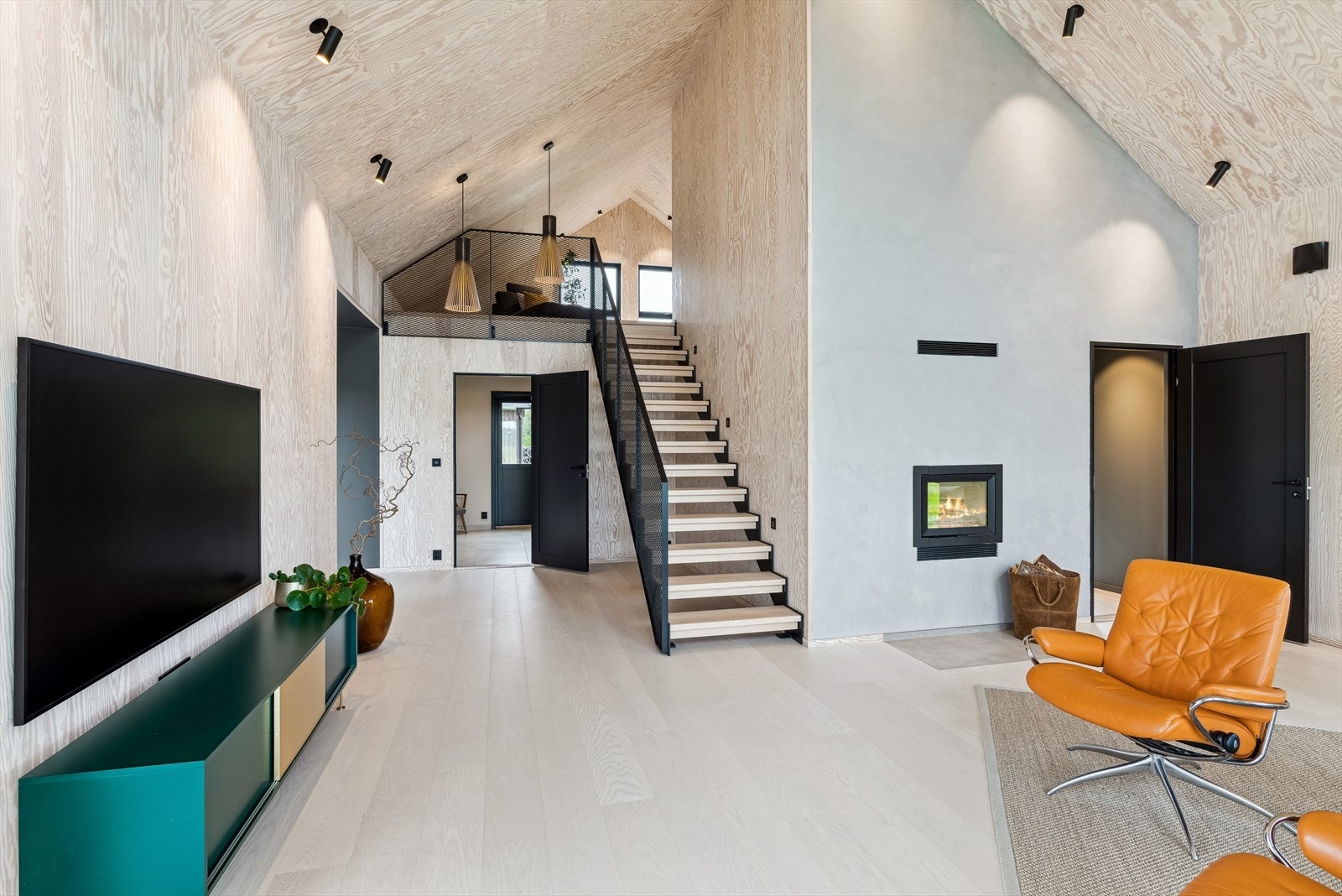 Det er også montert peisovn i denne stuen. Trappen er spesialbestilt og tar opp de sorte detaljene. Galleribilde