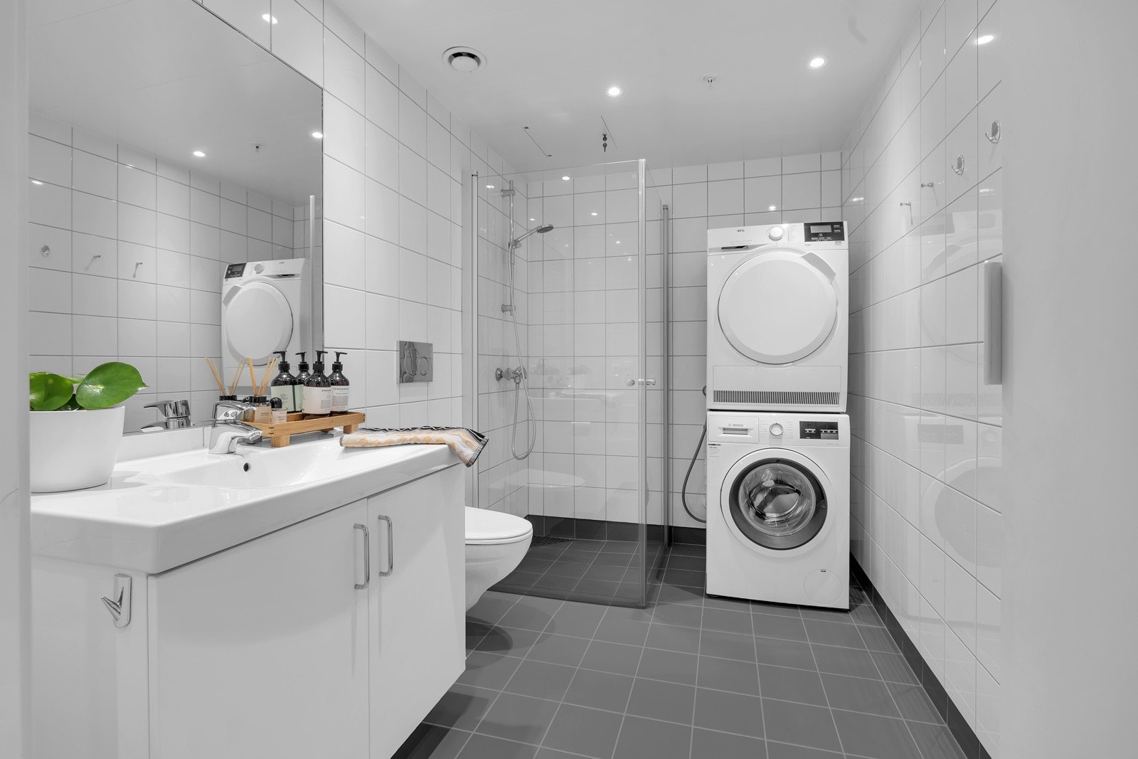 Opplegg for vaskemaskin og tørketrommel. Innfellbare glassdører i dusjsonen, innfelt belysnins i tak m.m. Galleribilde