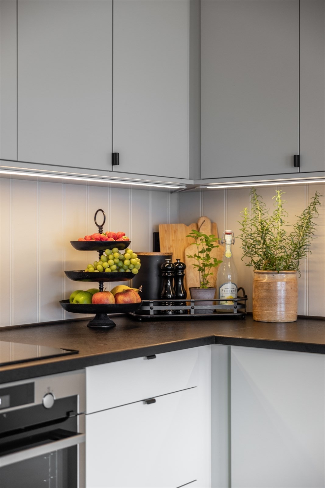 Gode arbeidsflater på laminert benkeplate i tøff, mørk fargetone hvor det er nedfelt kompositt vask i sort utførelse samt armatur og nedfelt induksjonskokeplate. Galleribilde