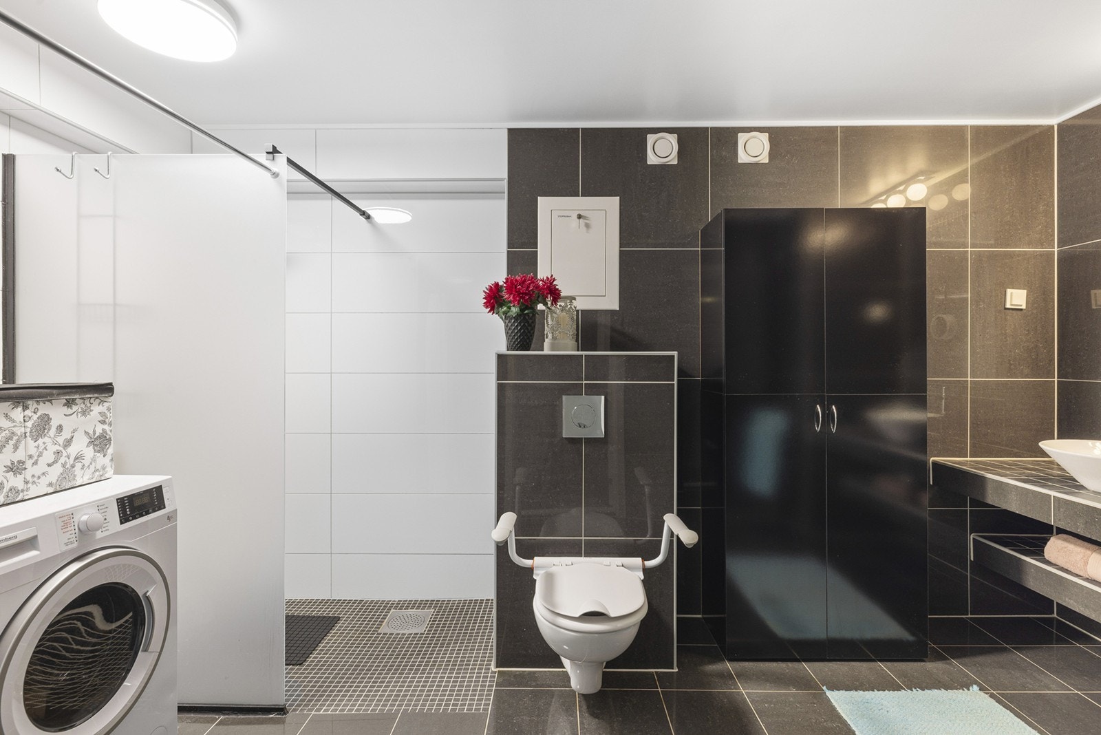 Leiligheten har et romslig og flislagt bad med gulvvarme. Det er opplegg for vaskemaskin og det er tilkoblet et vegghengt vannklosett. Galleribilde