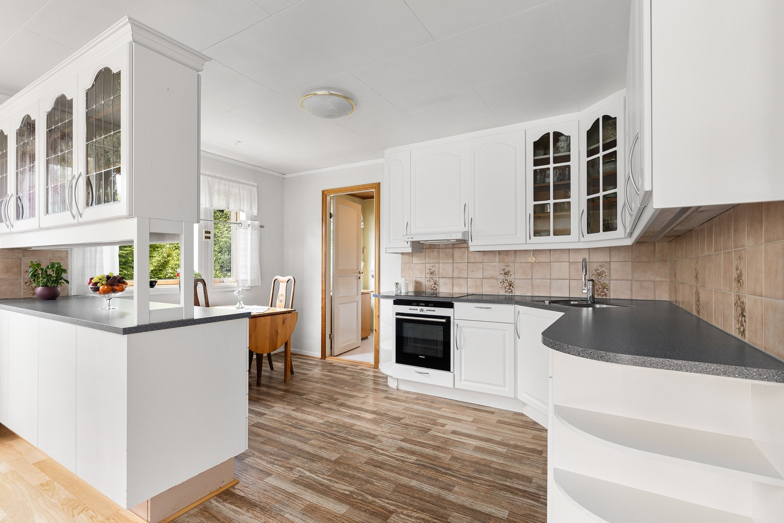 Kjøkkenet ligger naturlig tilbaketrukket fra stuen og er innredet med lyse slette flater og benkeplate av laminat. Galleribilde