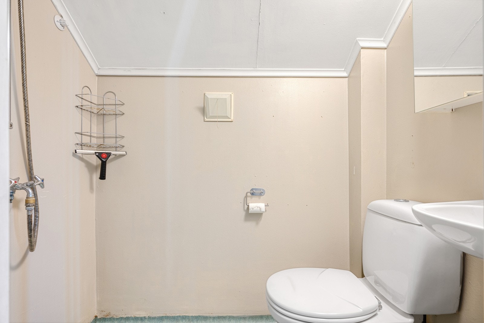 Badet har lav takhøyde og er utstyrt med toalett, servant, speilskap og åpen dusjløsning med dusjgarnityr på vegg. Galleribilde