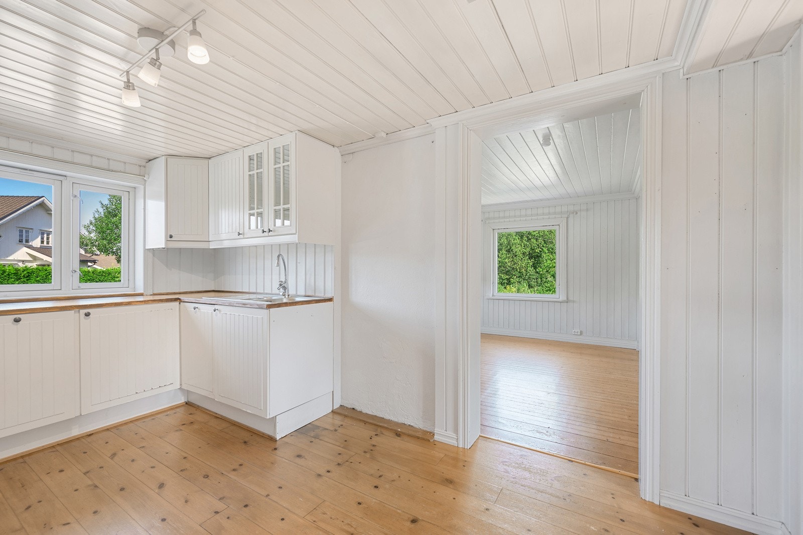 Fra kjøkkenet er det inngang til stuen. Rommene har lakkerte tregulv og malte panelvegger. Galleribilde