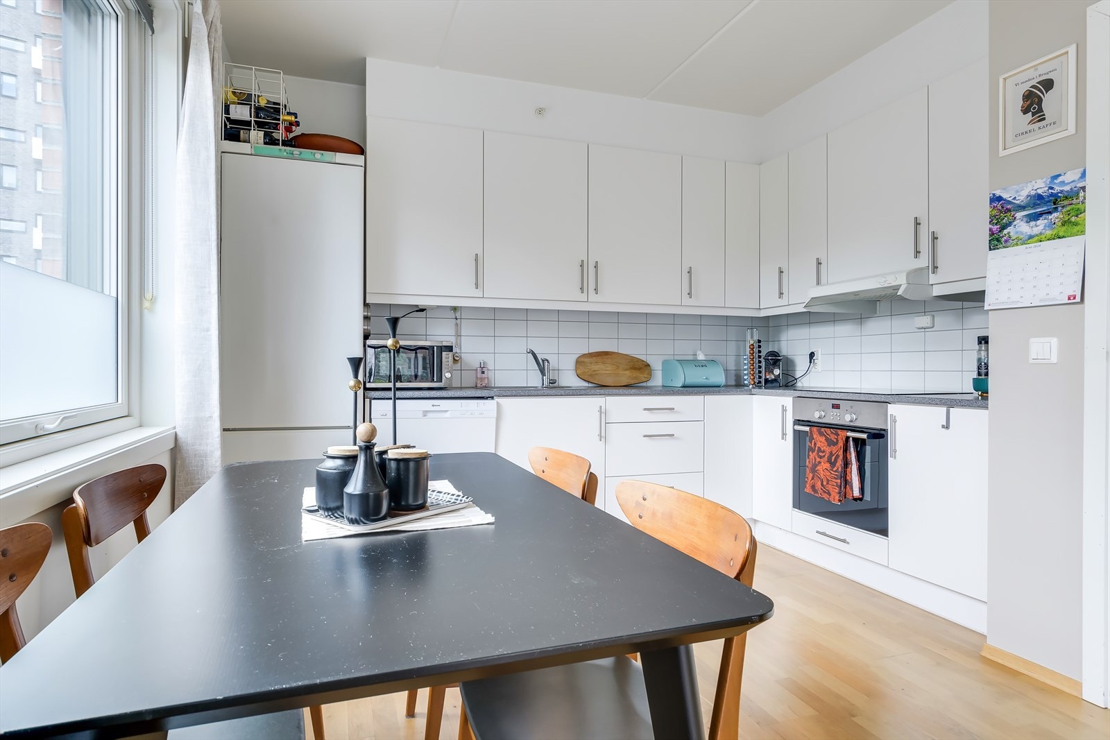 Det tidløse kjøkkenet er innredet med slette, hvite fronter. Galleribilde