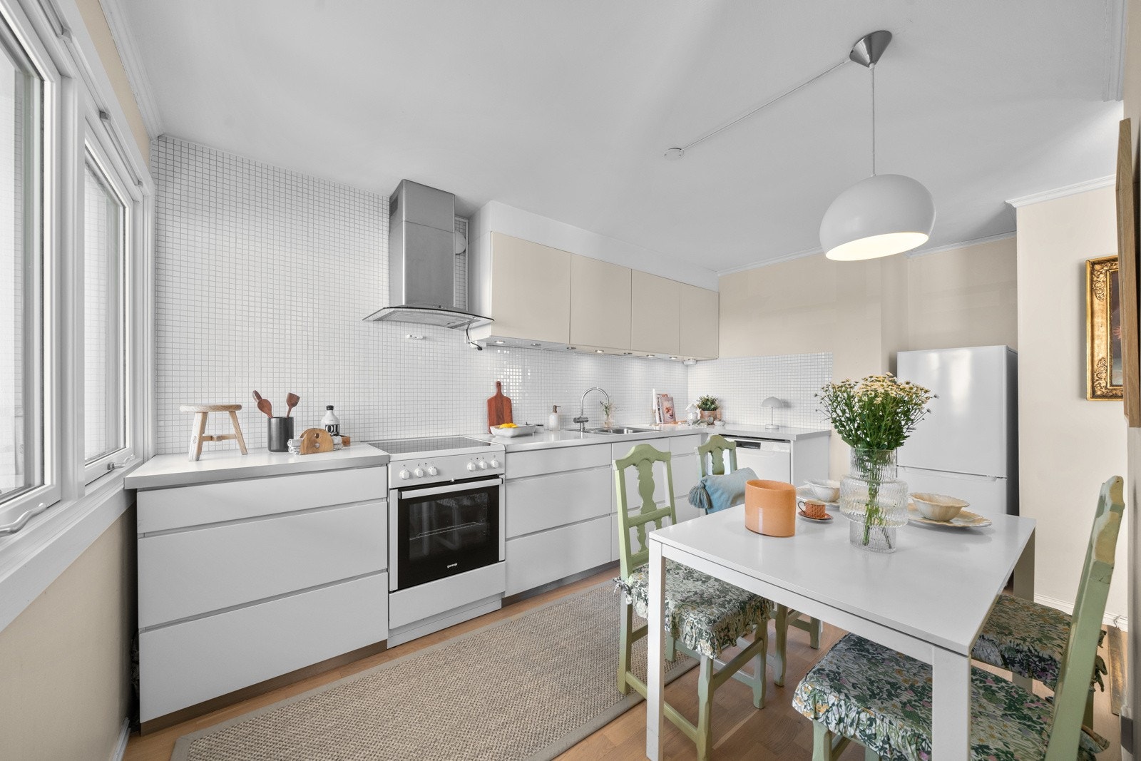 Lekkert kjøkken fra Kvik med hvite grepsfrie fronter og mosaikkfliser på veggen, samt overskap med benkebelysning Galleribilde