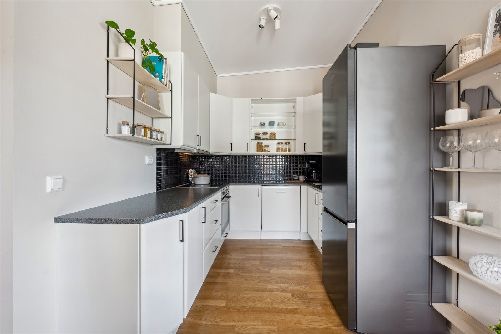 Kjøkkenet er velutstyrt med rikelig skap- og benkeplass, lyse overflater og en mørk benkeplate som skaper en fin kontrast. Galleribilde