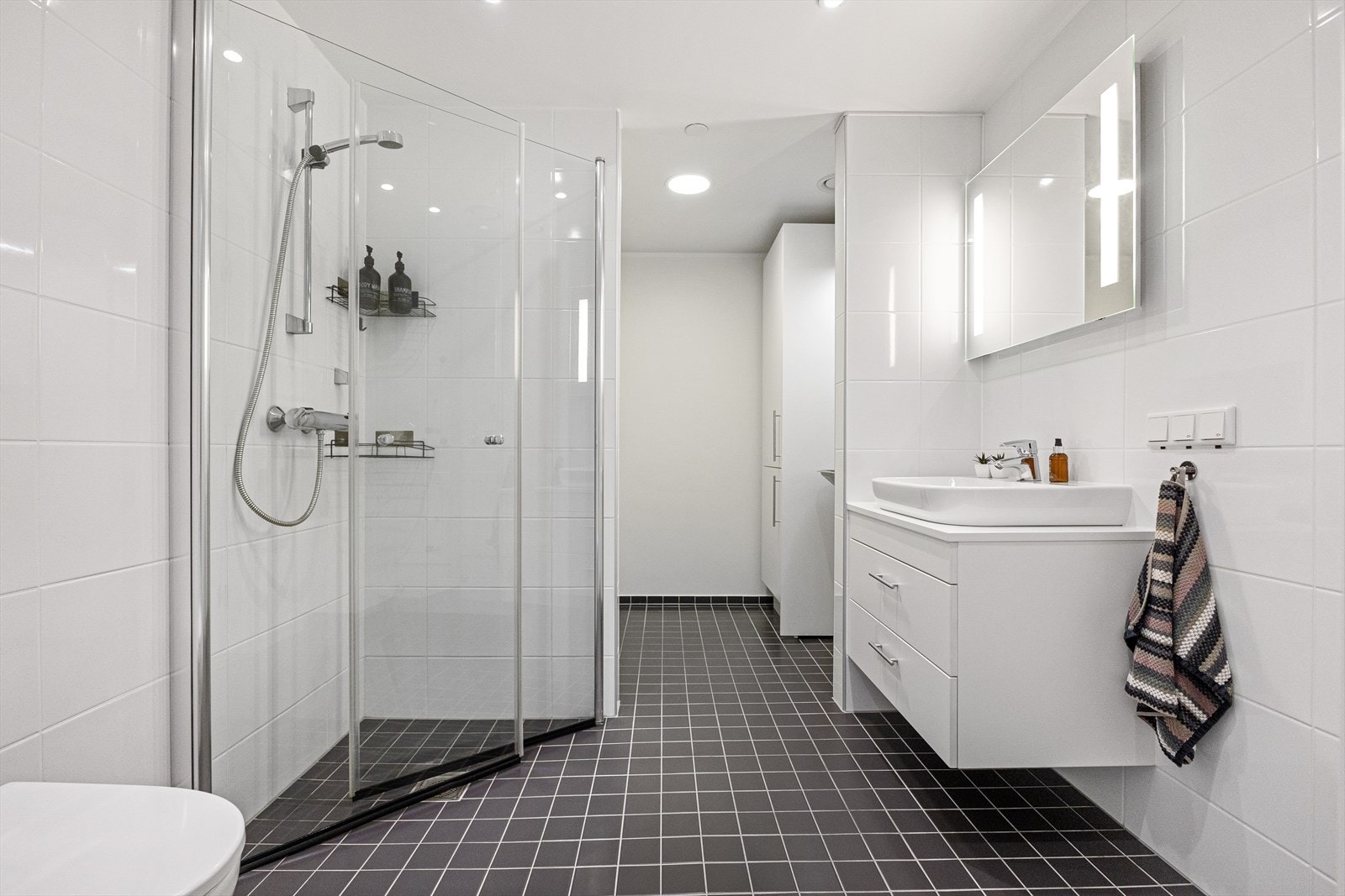 Stort bad med vaskeromsdel. Varme i gulv, pen innredning med stilig servant og speil med LED belysning. Innfellbare dusjdører. Komplett flislagt. Galleribilde