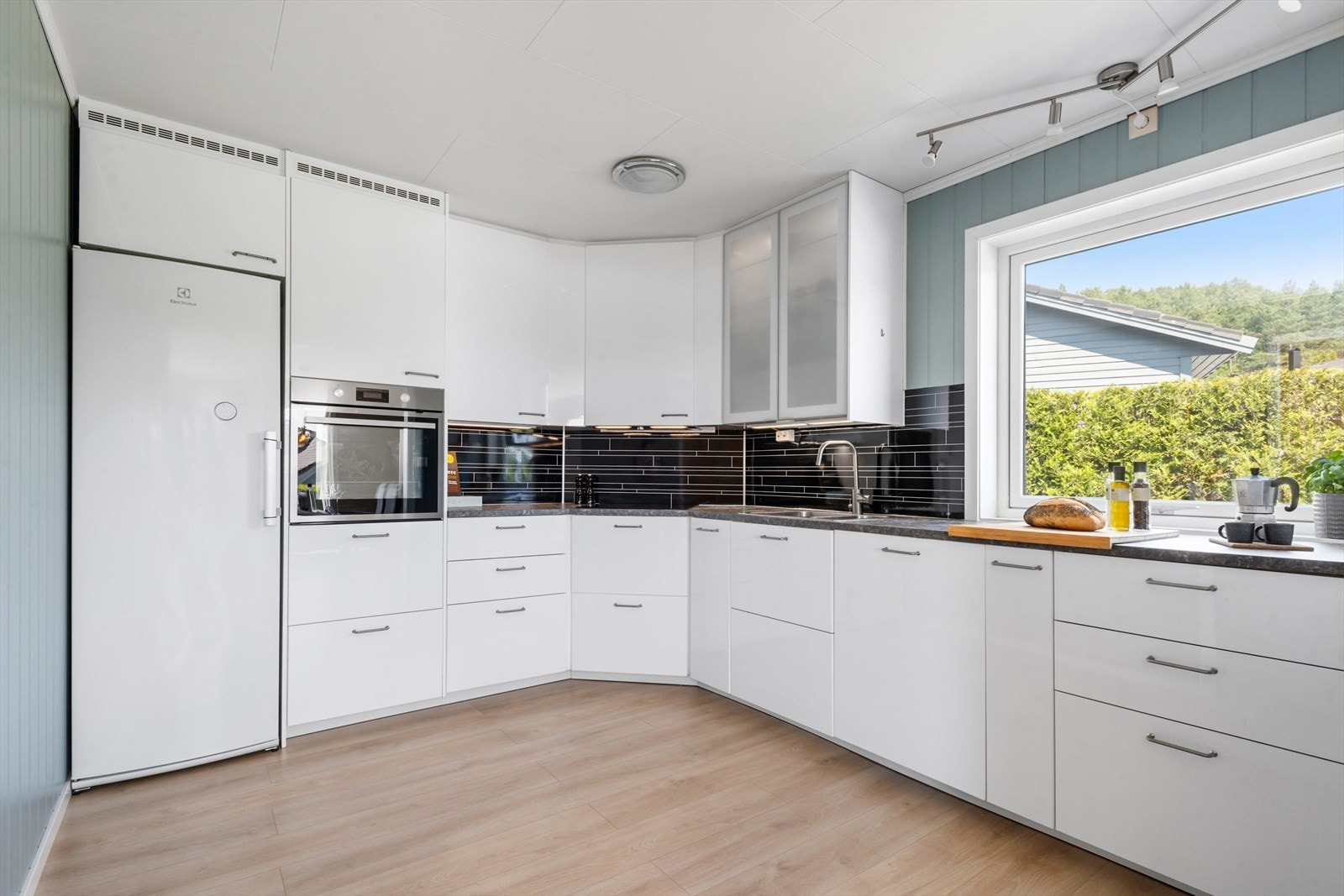 L - formet Ikea kjøkkeninnredning i hvit høyglans med laminat benkeplate, samt dempefunksjon i skuffer og skap. Galleribilde