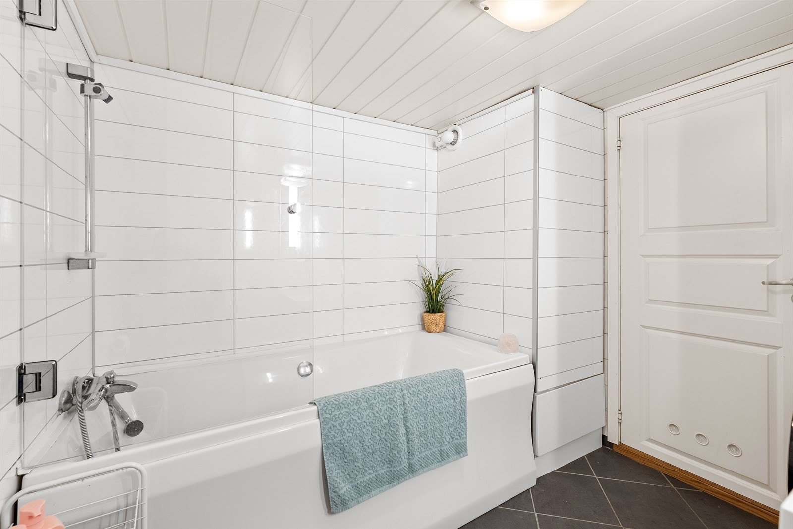 Her finner man et kombinert vaskerom/bad pent innredet med mørke fliser på gulvet og lyse baderomsplater på vegg. Galleribilde
