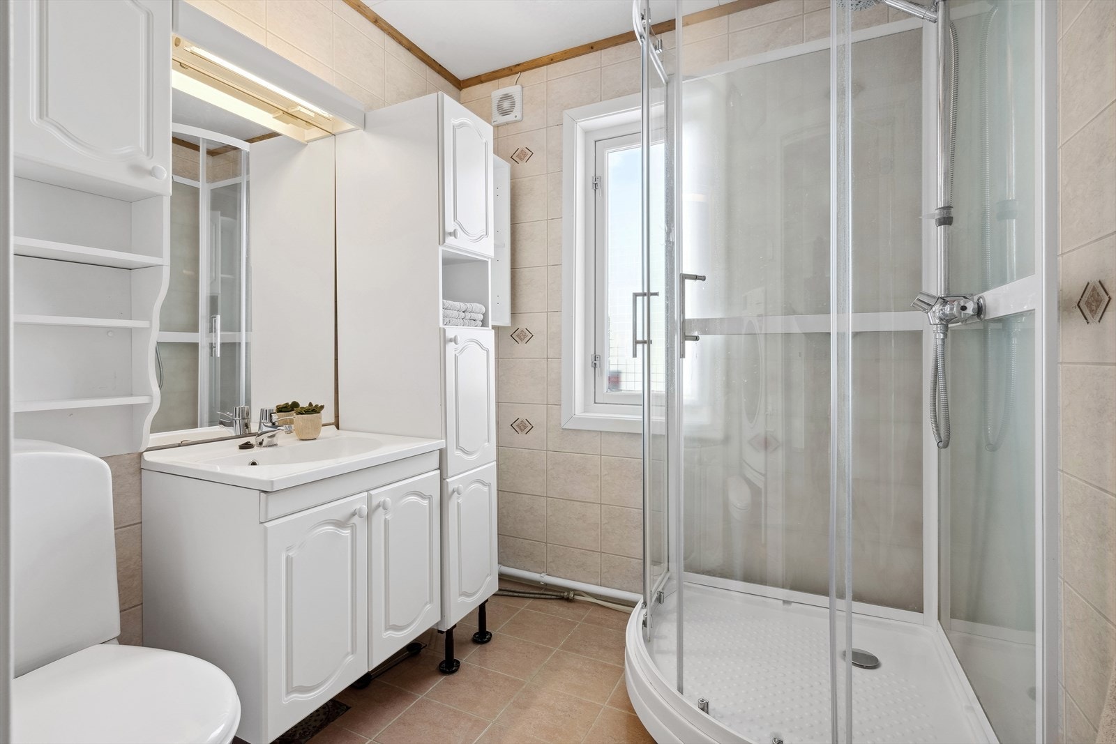 Badet/vaskerommet består av speil, servant med møbel, oppbevaringsskap, toalett, dusjkabinett og opplegg for vaskemaskin. Galleribilde