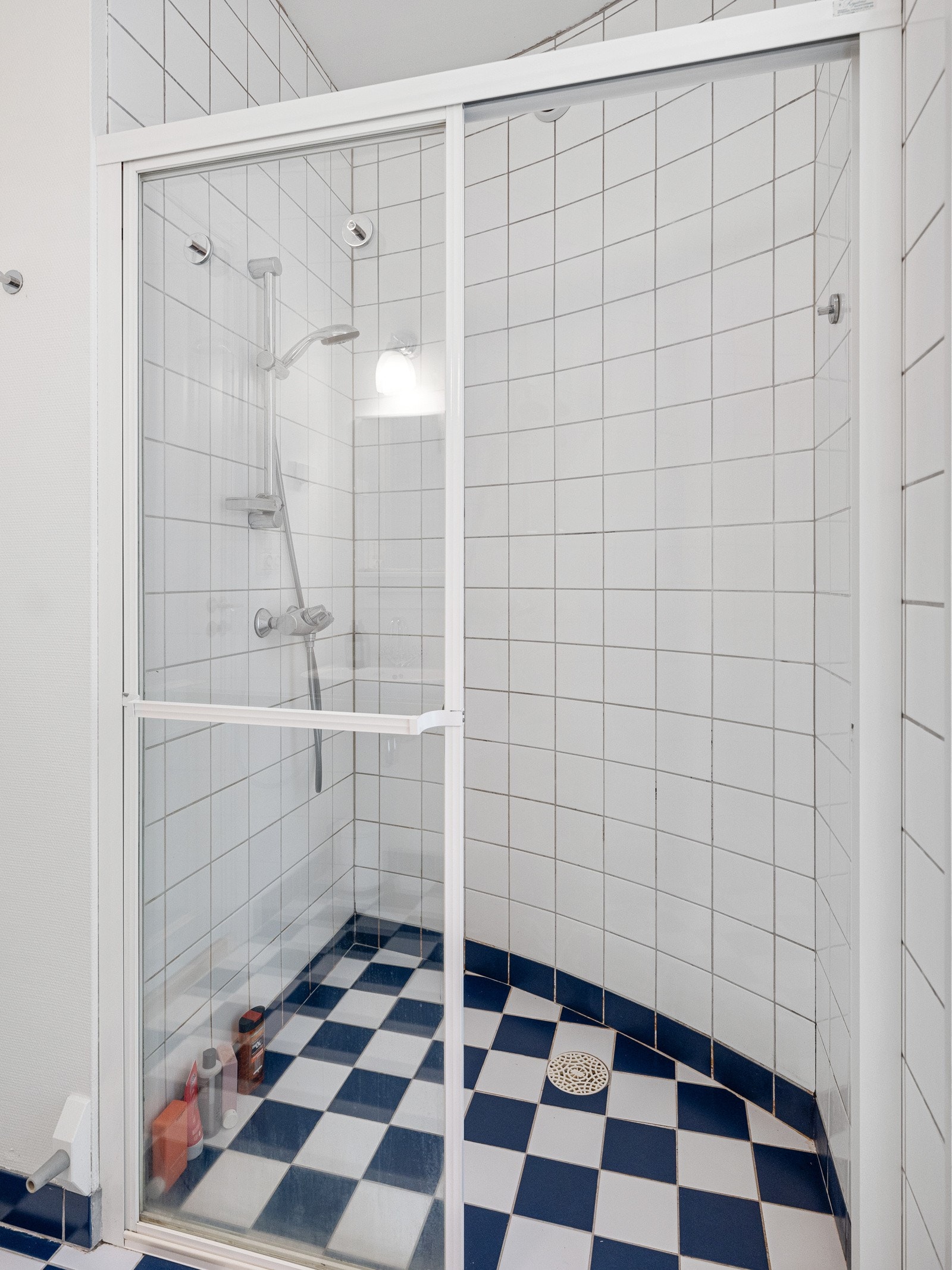 Badet har en klassisk stil med hvite og blå gulvfliser lagt i sjakkmønster. Veggene har to hvitmalte vegger mens resten er kledd med hvite fliser, inkludert i dusjhjørnet. Galleribilde