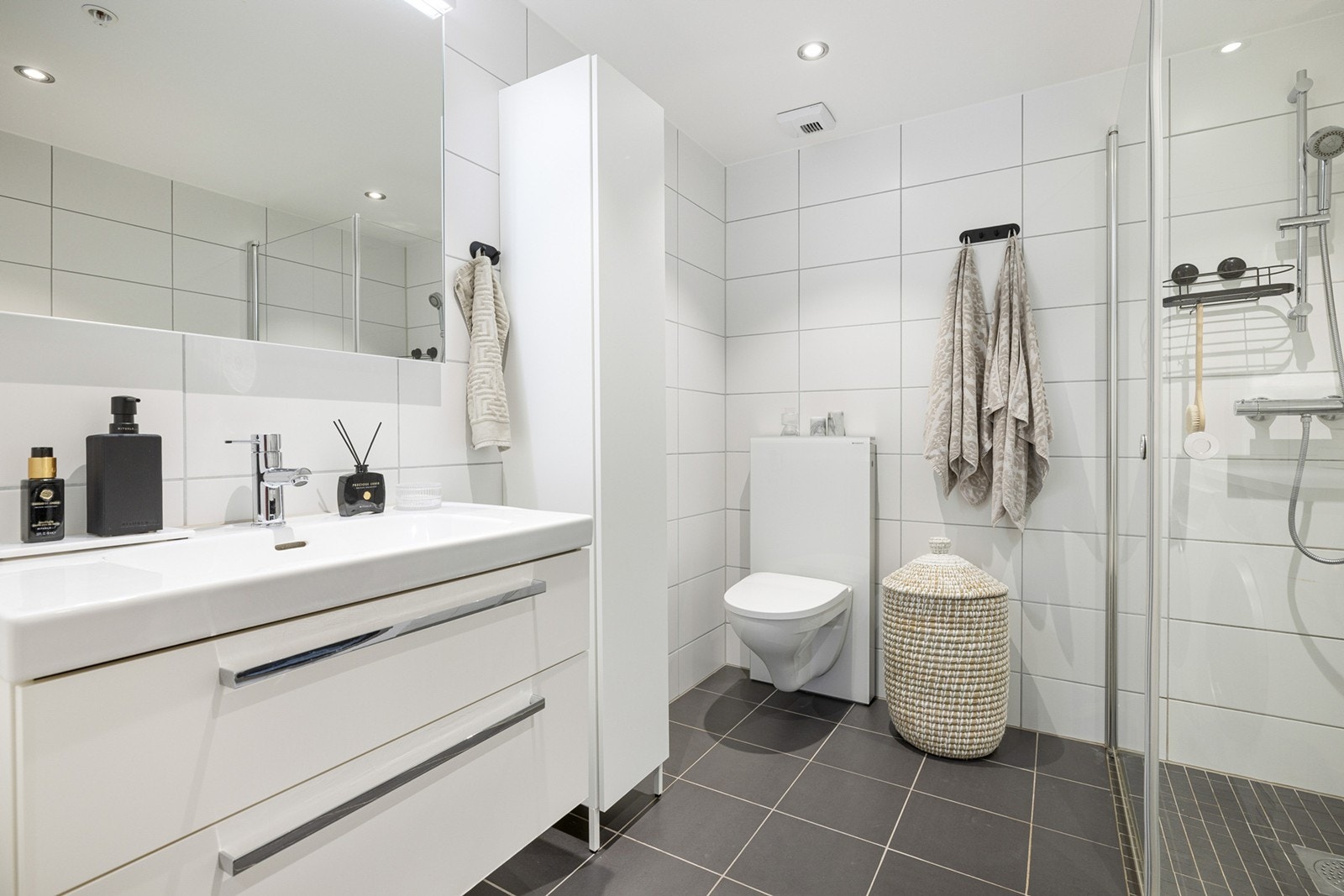 Et dusjhjørne med innfellbare dører. Den øvrige innredningen består av et underskap/sideskap, servant, speil, armatur og stikk. Badet har downlights og varme i gulvet. Galleribilde