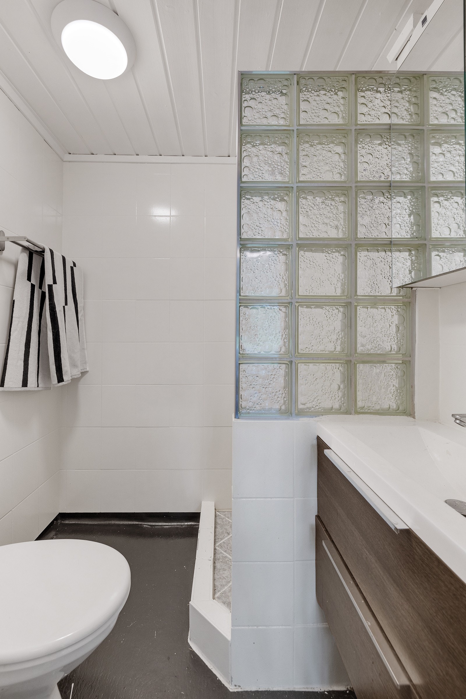 Bad med toalett, dusj og innredning med servant, skuffer og speil. Galleribilde