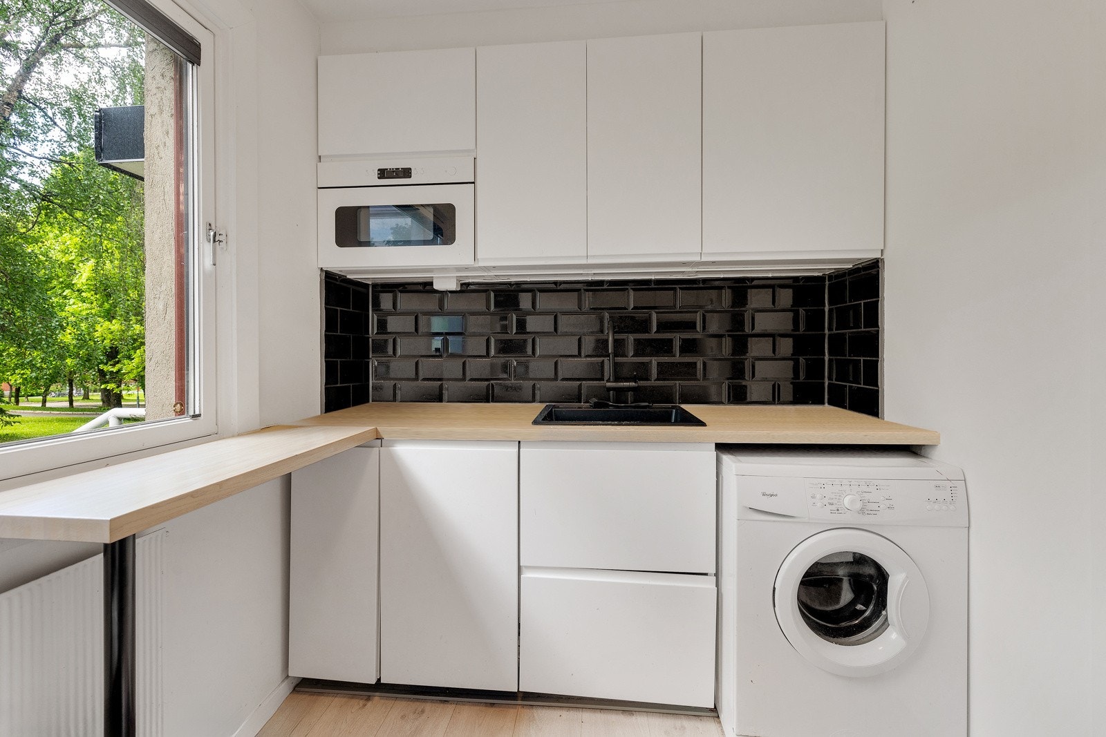 Moderne kjøkken med integrerte hvitevarer, fliser over benk og opplegg for vaskemaskin. Galleribilde