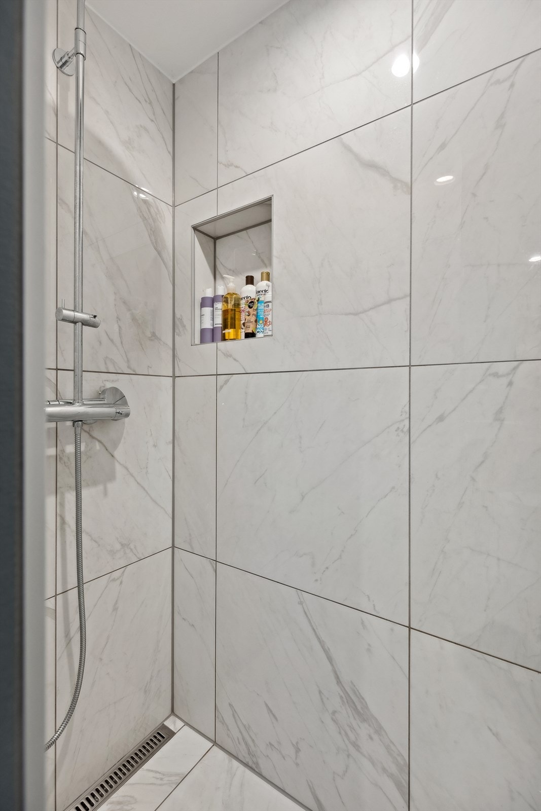 Badet er innredet med et veggmontert toalett, dusjhjørne, baderomsinnredning med toppmontert servant og speil. Galleribilde