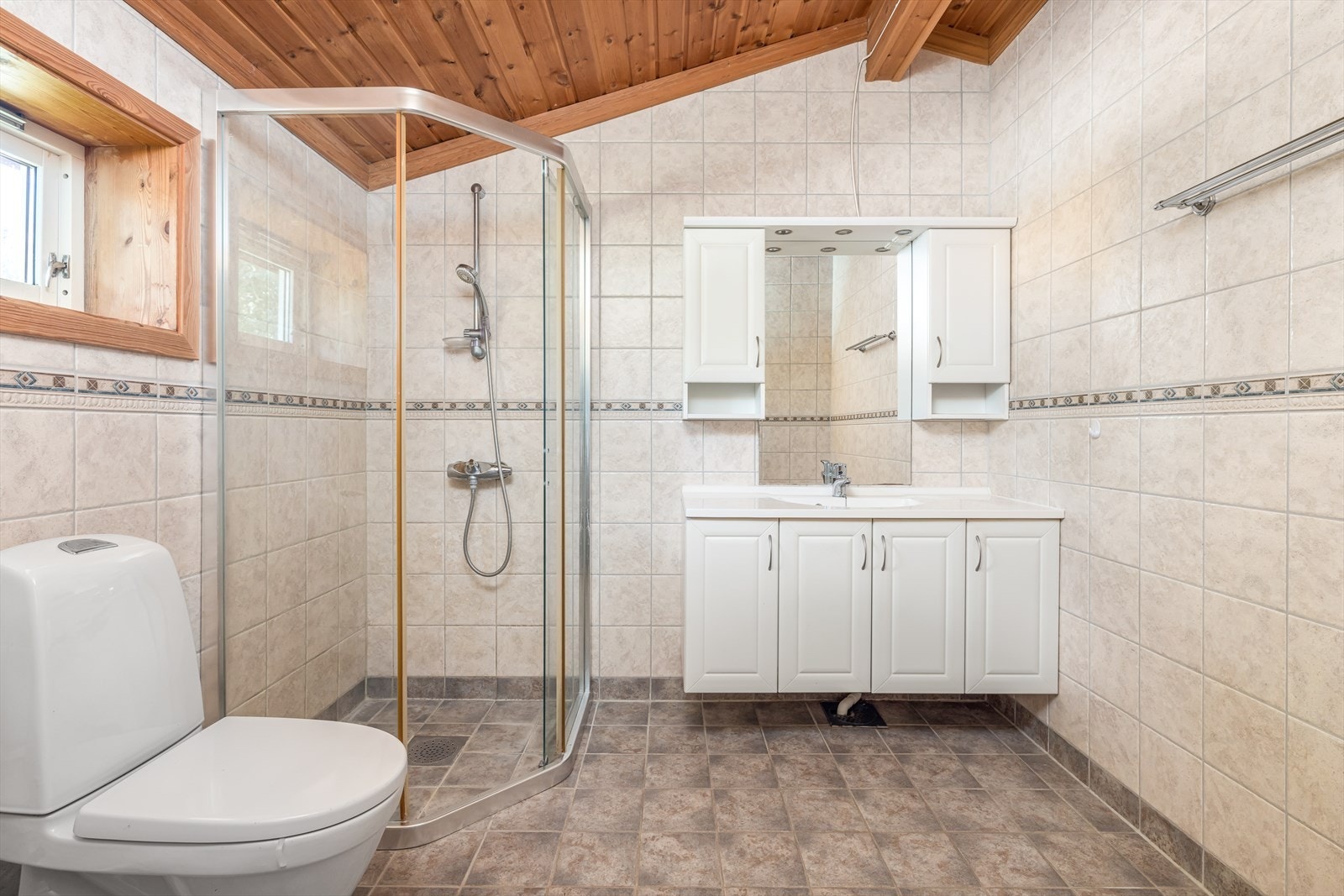 Pent bad innredet med servant på innredning, toalett og dusjhjørne. Galleribilde