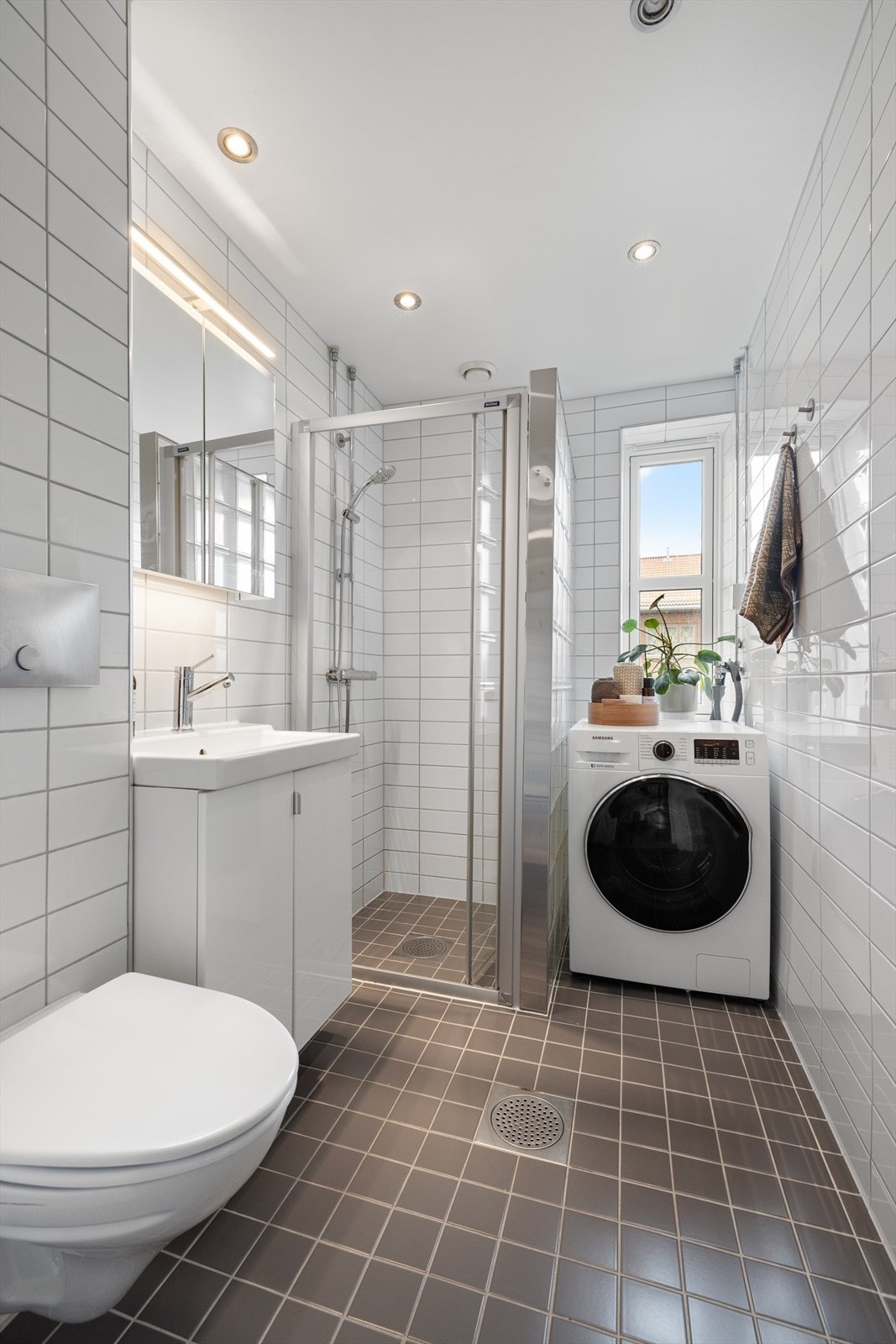 Pent, tidløst bad med flislagte overflater, behagelig gulvvarme og downlights i himling. Det er opplegg for vaskemaskin Galleribilde