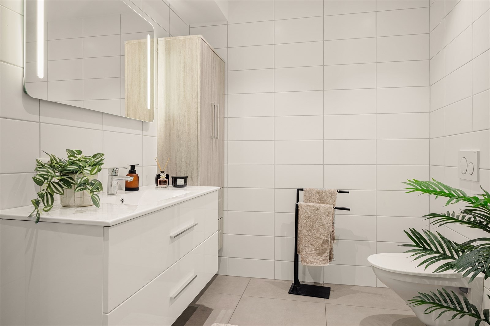 Det lekre badet har en lun farge på flisene og et pent møblement. Galleribilde