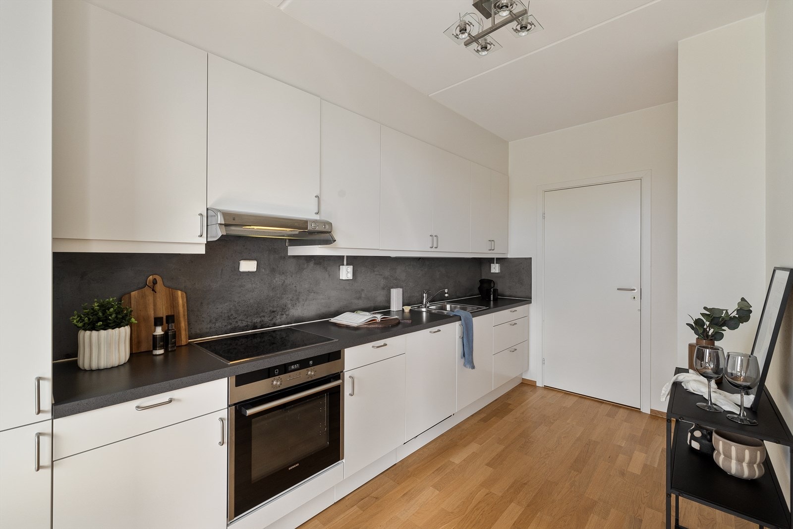 Videre er kjøkkenet innredet med integrerte hvitevarer som kjøl/fryseskap, oppvaskmaskin, induksjonstopp og stekeovn. Det er montert komfyrvakt og avtrekk via sentralt avtrekksanlegg i bygget. Galleribilde