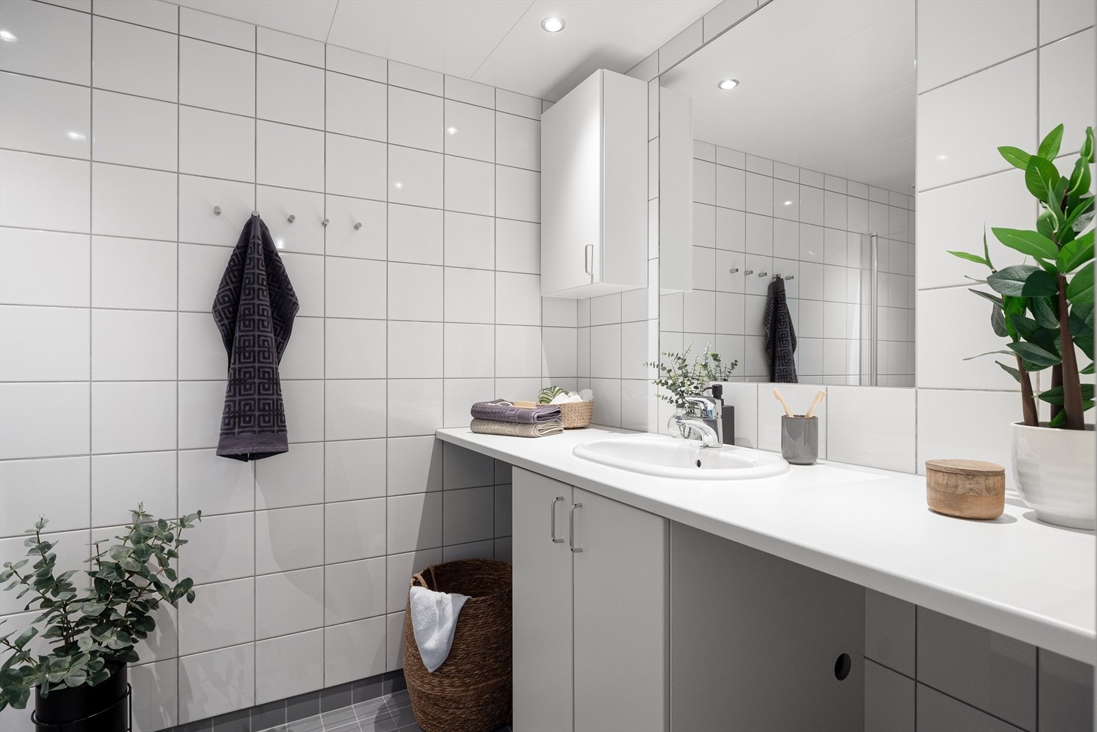 Baderomsinnredningen består av veggmontert benkeplate med servantskap og nedfelt servant samt vegghengt speil over servant. Galleribilde