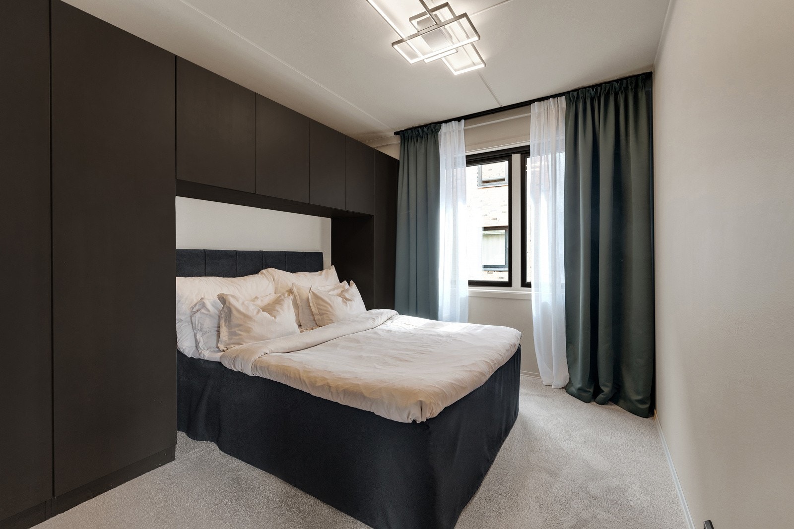 Et nydelig soverom i leiligheten med plassbygd garderobeløsning på den ene veggen med mye rom for oppbevaring. Galleribilde