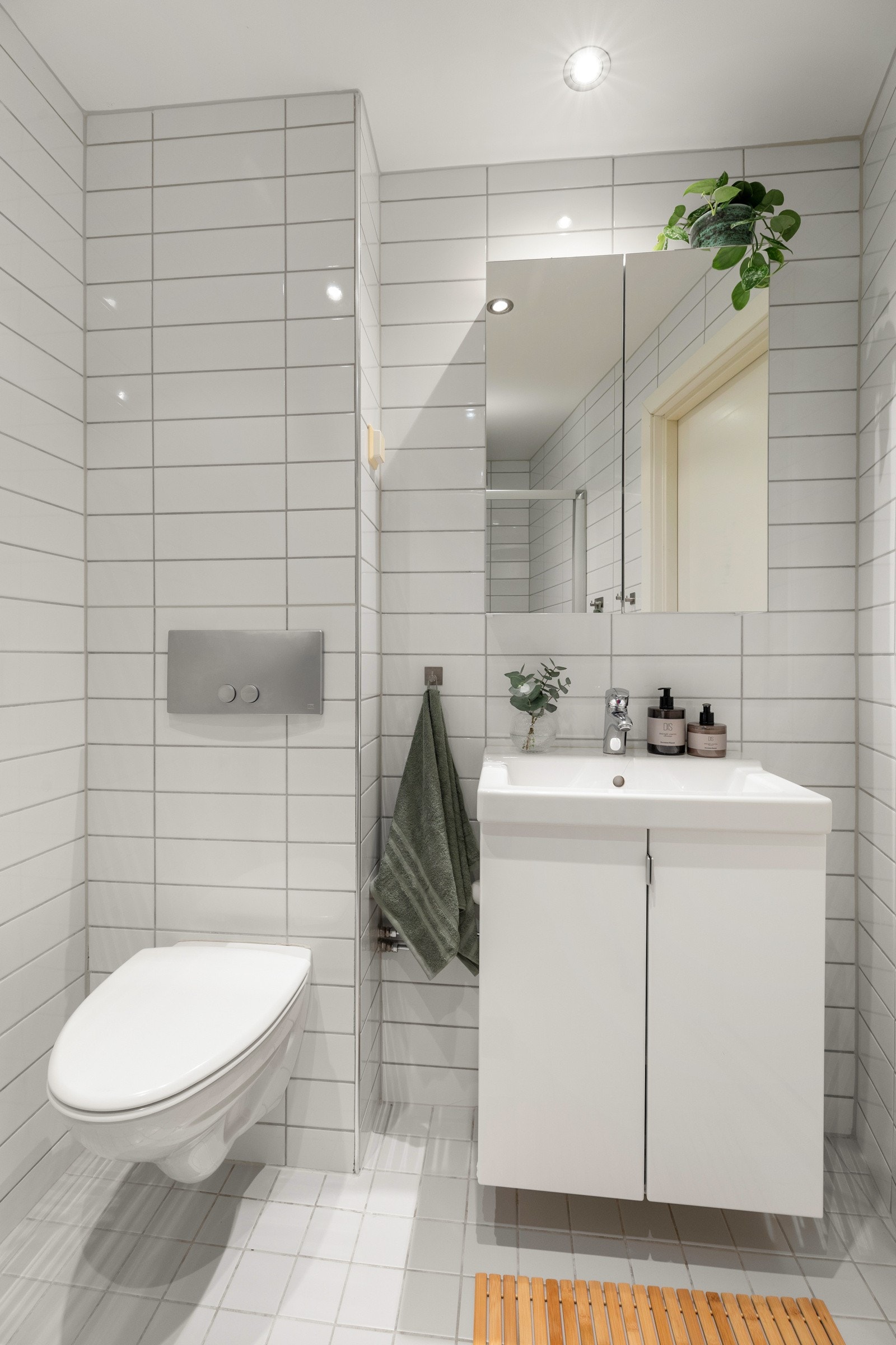 Det inneholder et servantskap med speilskap over, et vegghengt toalett og en dusjsone med skyvedør i glass og regnfallsdusj. Galleribilde