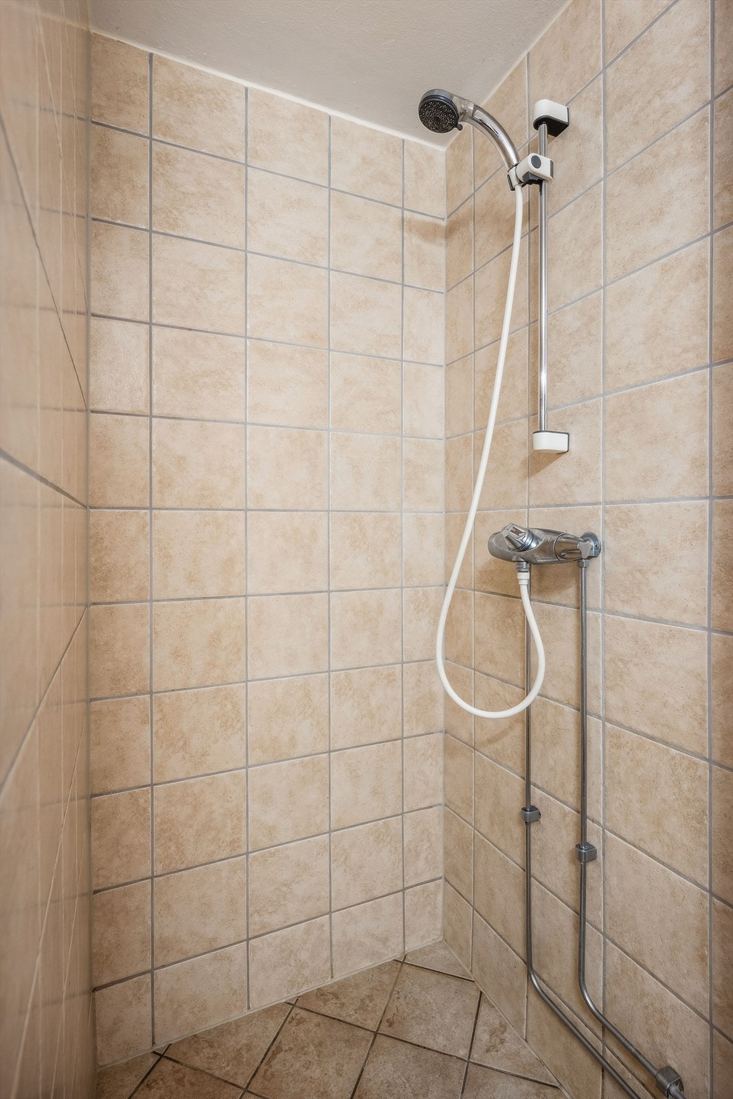 Badet har fliser på gulv og vegger, standard innredning, gulvvarme og dusjhjørne. Galleribilde