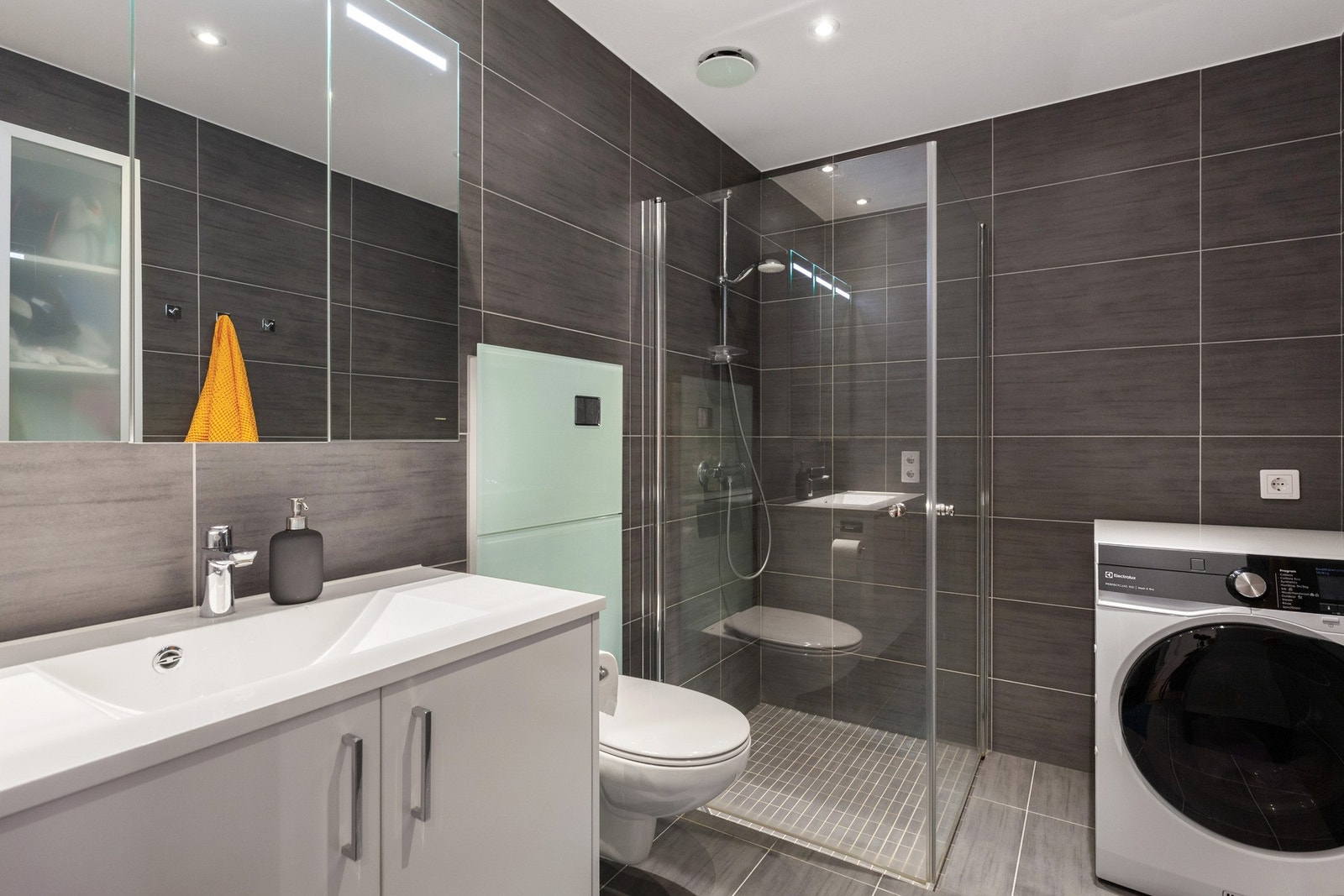 Pent flislagt bad/vaskerom. Toalett med Unopax Air med luktfritt toalett. Mosaikkfliser i dusjsone. Galleribilde