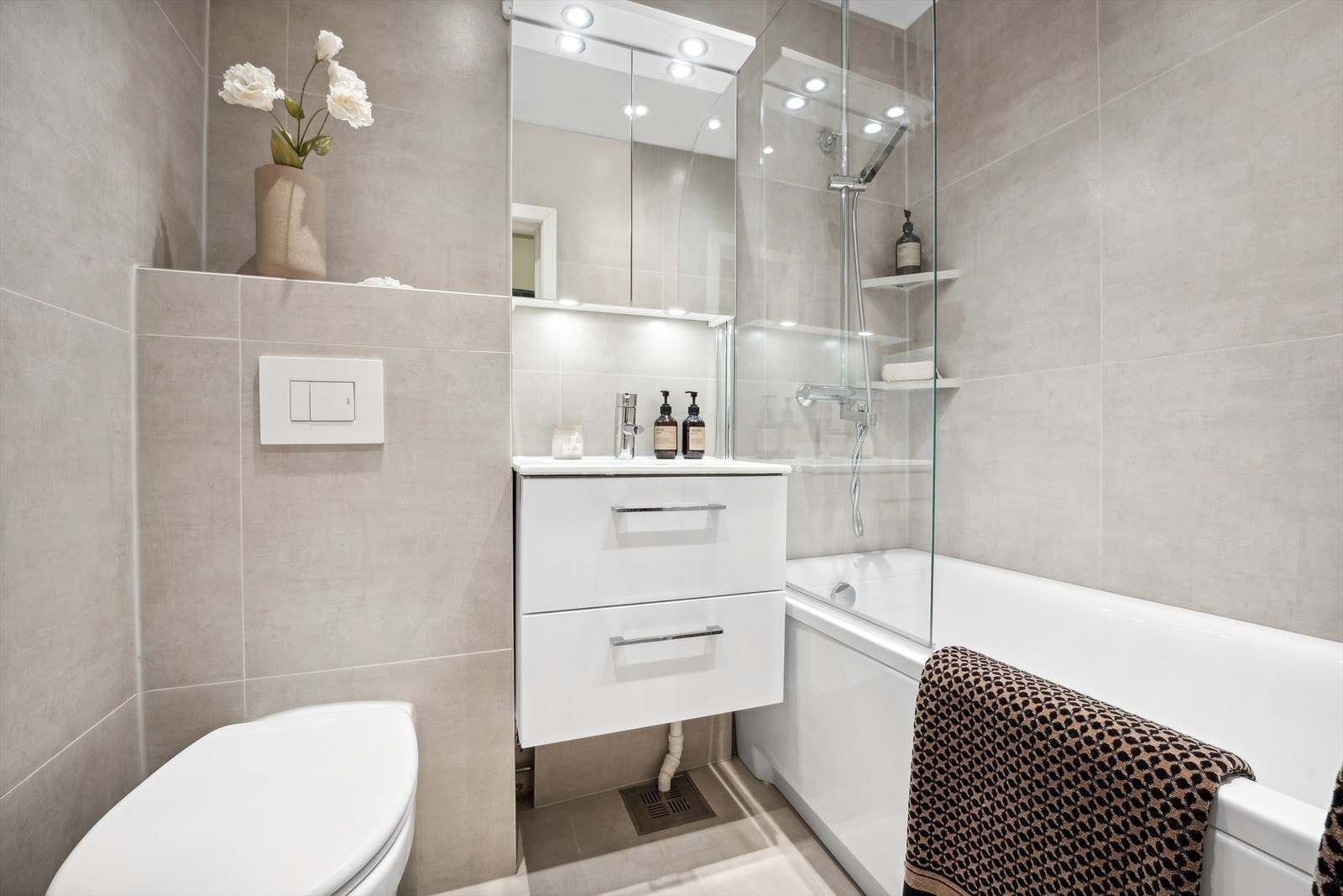 Delikat og stilrent baderom med lun gulvvarme som gir rommet en behagelig atmosfære - her kan man lene seg tilbake i badekaret og unne seg selv litt velfortjent velvære Galleribilde