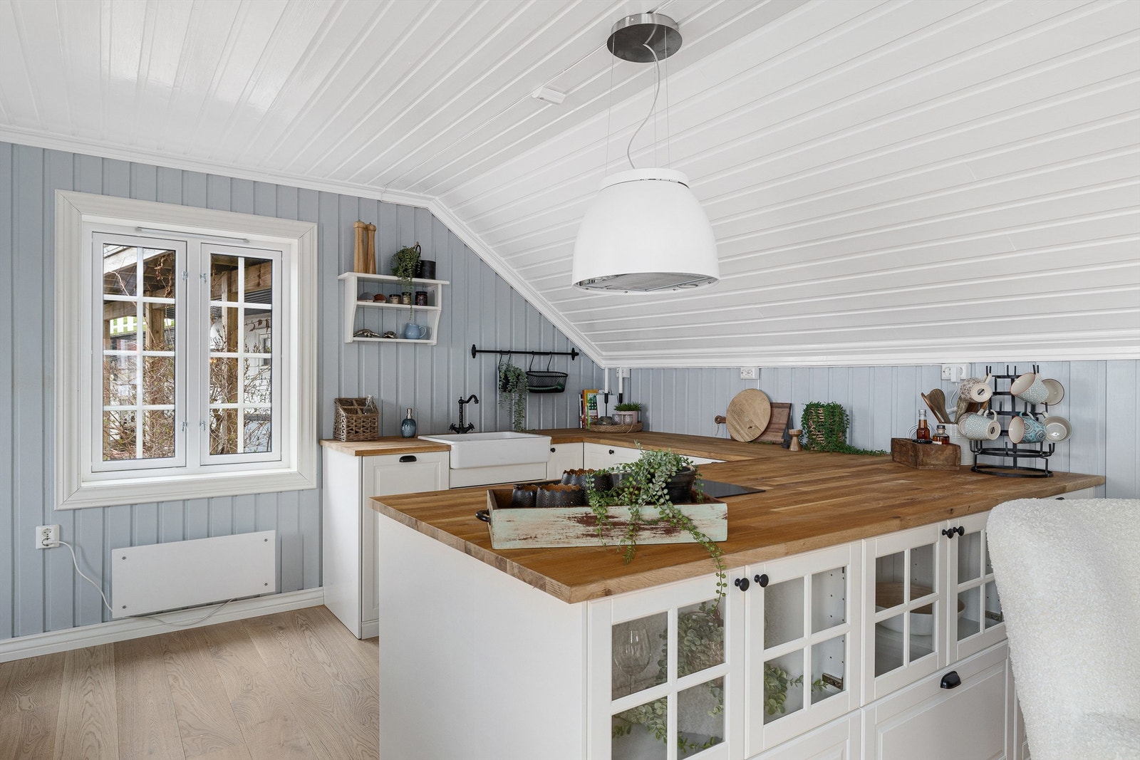 Benkeplate i eik og porselensvask passer fint til husets stil. Smart bruk av vinduer i skapene gir et vitrinepreget og luftigere uttrykk mot stua. Galleribilde