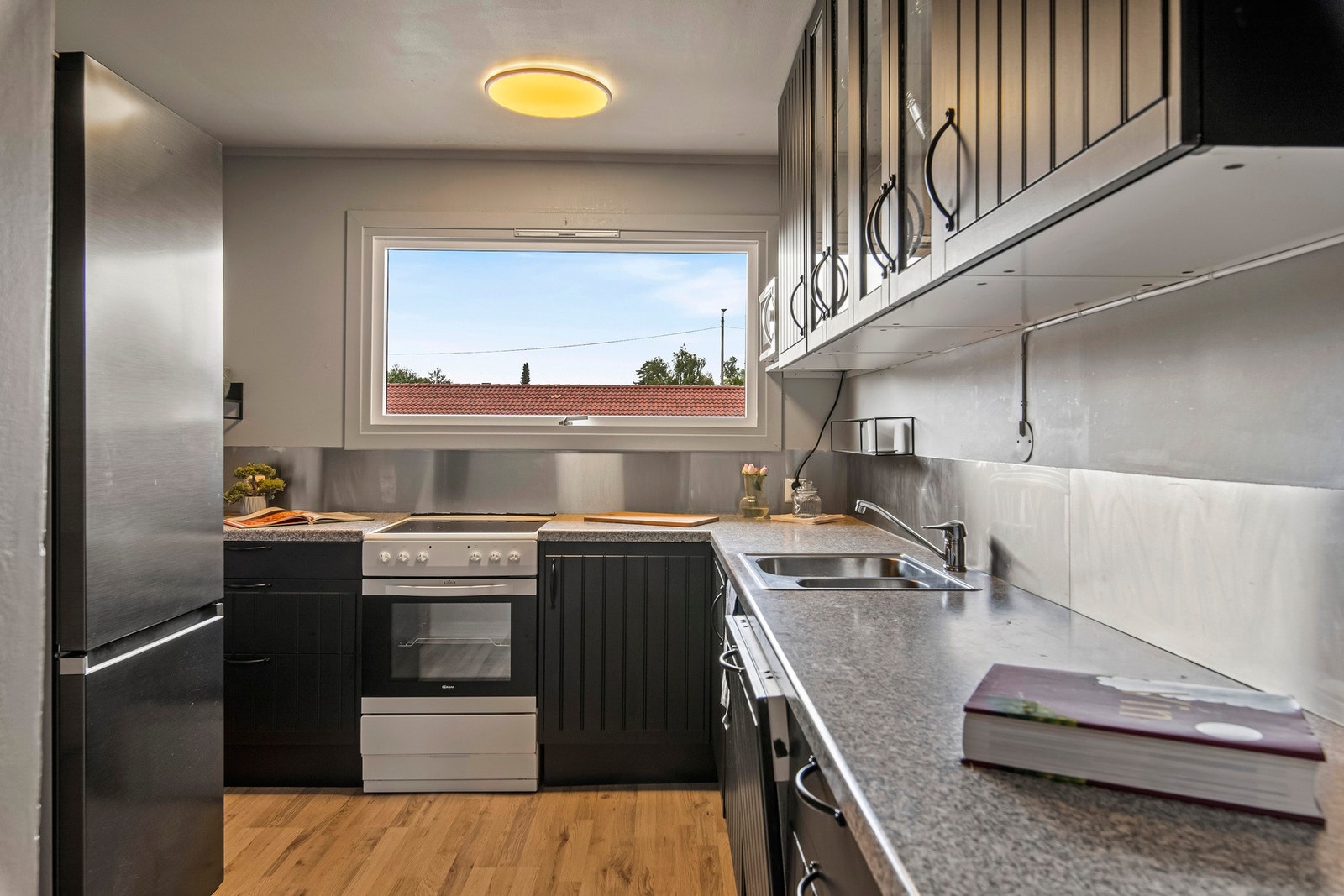 Kjøkkenet er med kjøkkeninnredning i malt profilert utførelse. Laminat benkeplate med aluminiumsplate over benk. Integrert oppvaskmaskin. Galleribilde