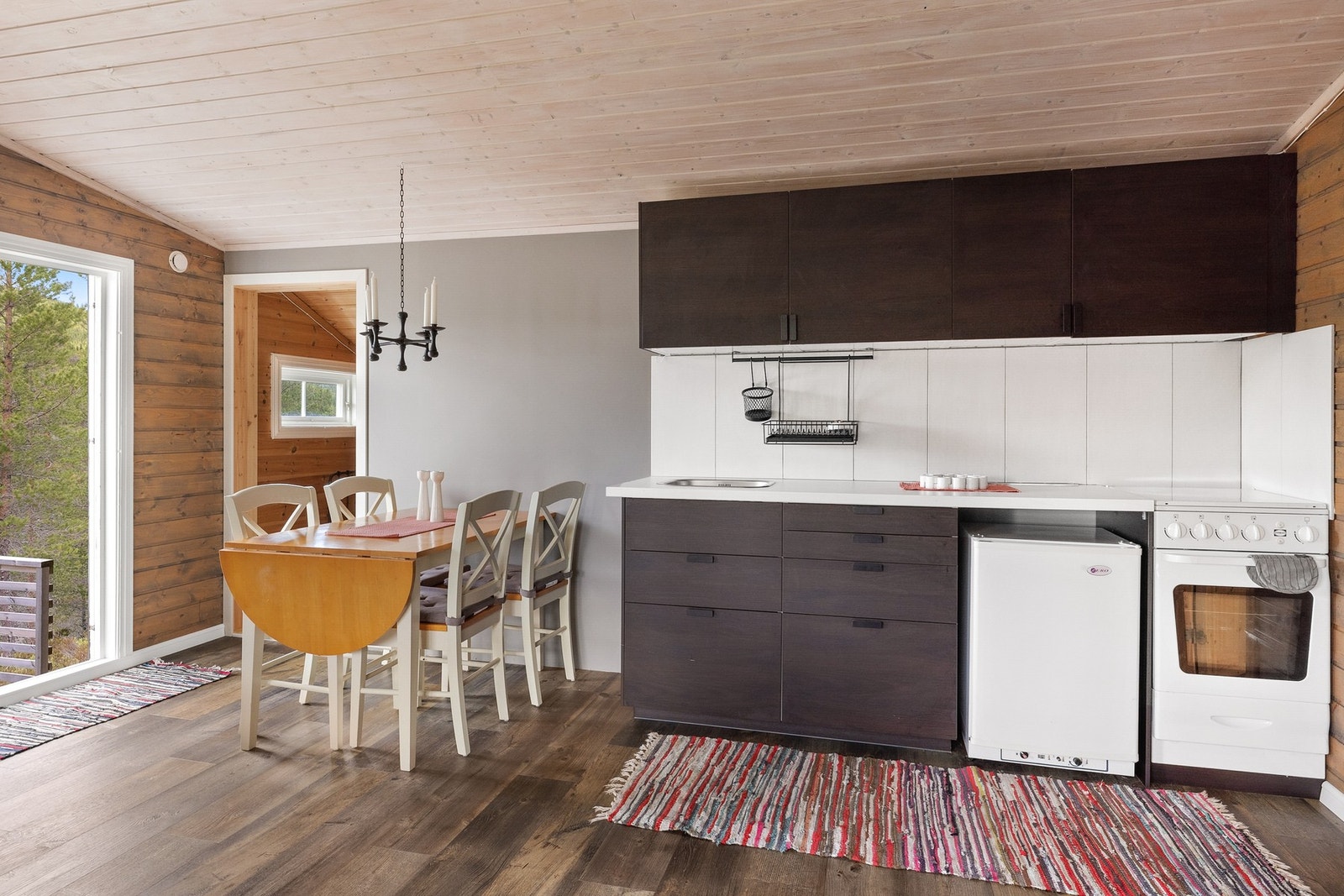 Kjøkkeninnredning på en vegg med over- og underskap, laminat benkeplate med skyllekum med avløp under hytta Galleribilde