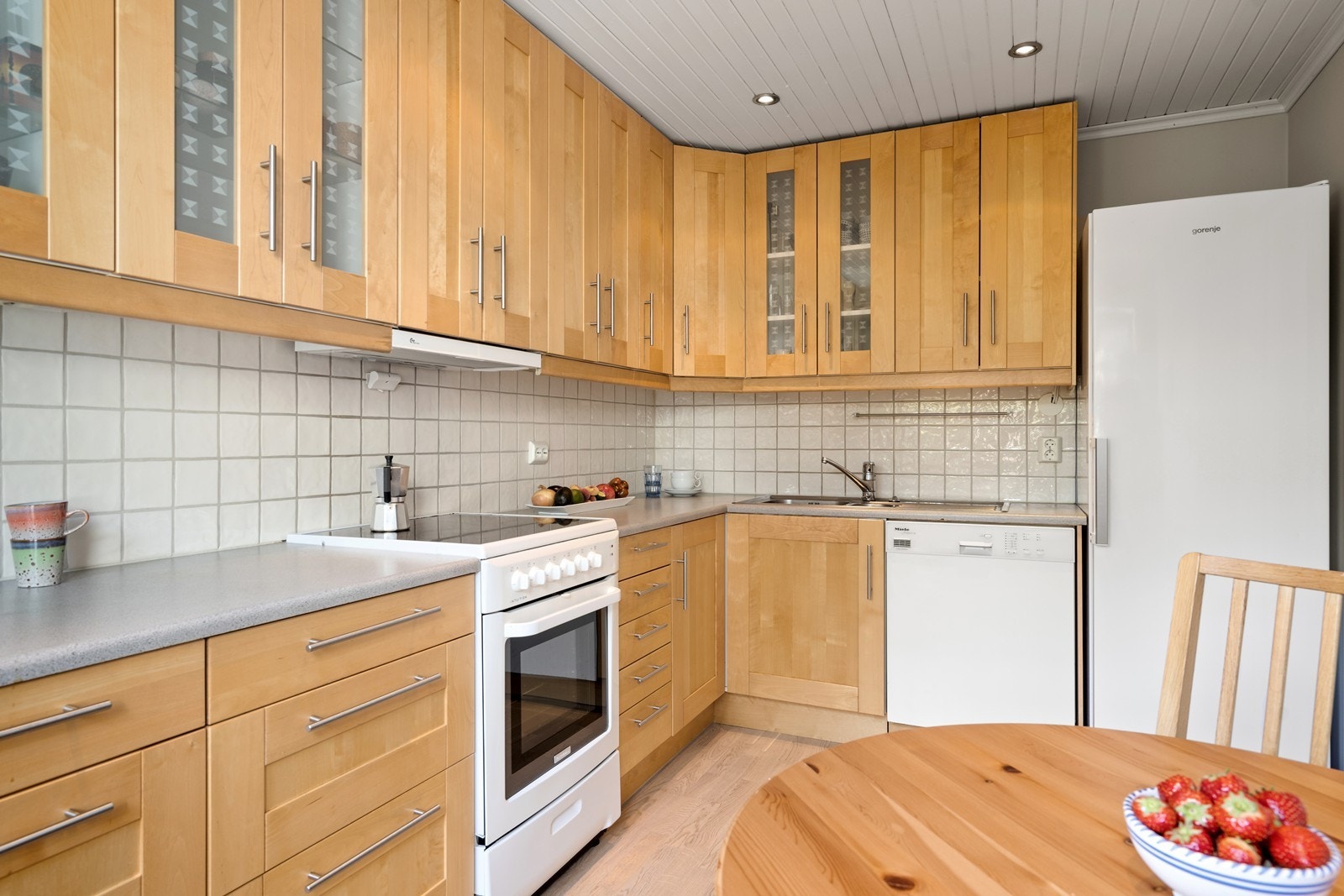 Benkeplaten er av laminat med nedfelt kum. Pene fliser og belysning over benken. Galleribilde