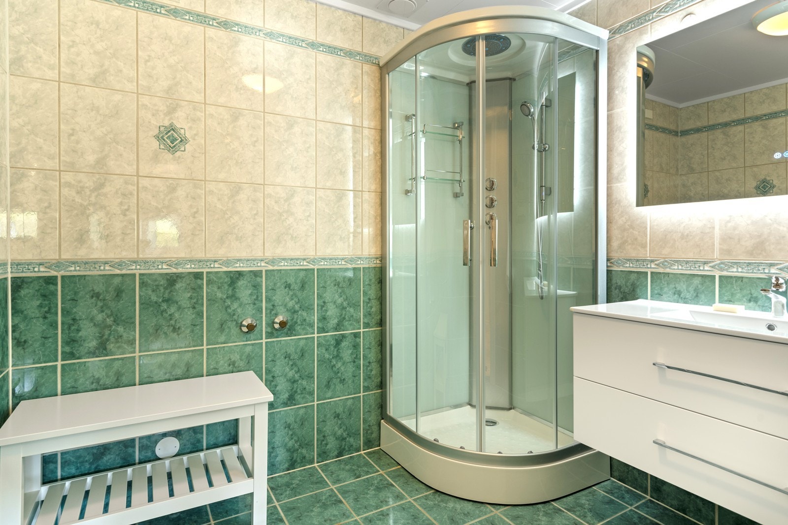 Flislagt bad fra 1997 med himlingsplater i tak og varmekabler i gulv. Rommet har innredning med servant med underskap og dusjkabinett. Hulltaking er foretatt uten å påvise unormale forhold på fukt. Galleribilde