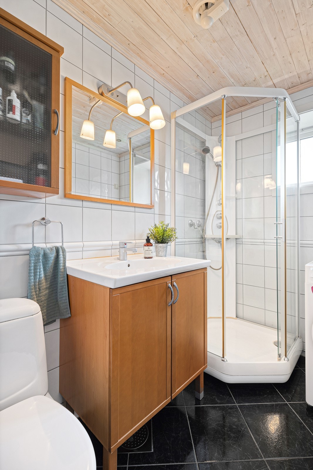 Badet er innredet med dusjkabinett, toalett, heldekkende servant i baderomsinnredning og opplegg til vaskemaskin Galleribilde