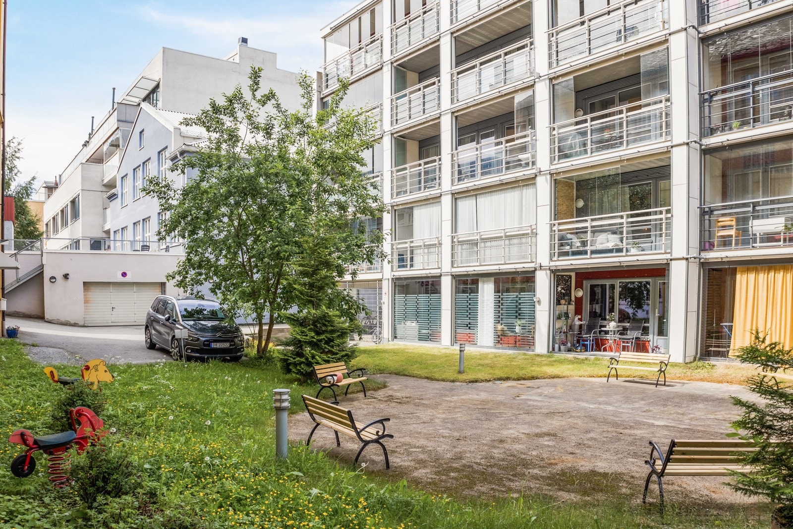 Hage bak bygningen med diverse beplantning og flere sitteplasser. Galleribilde