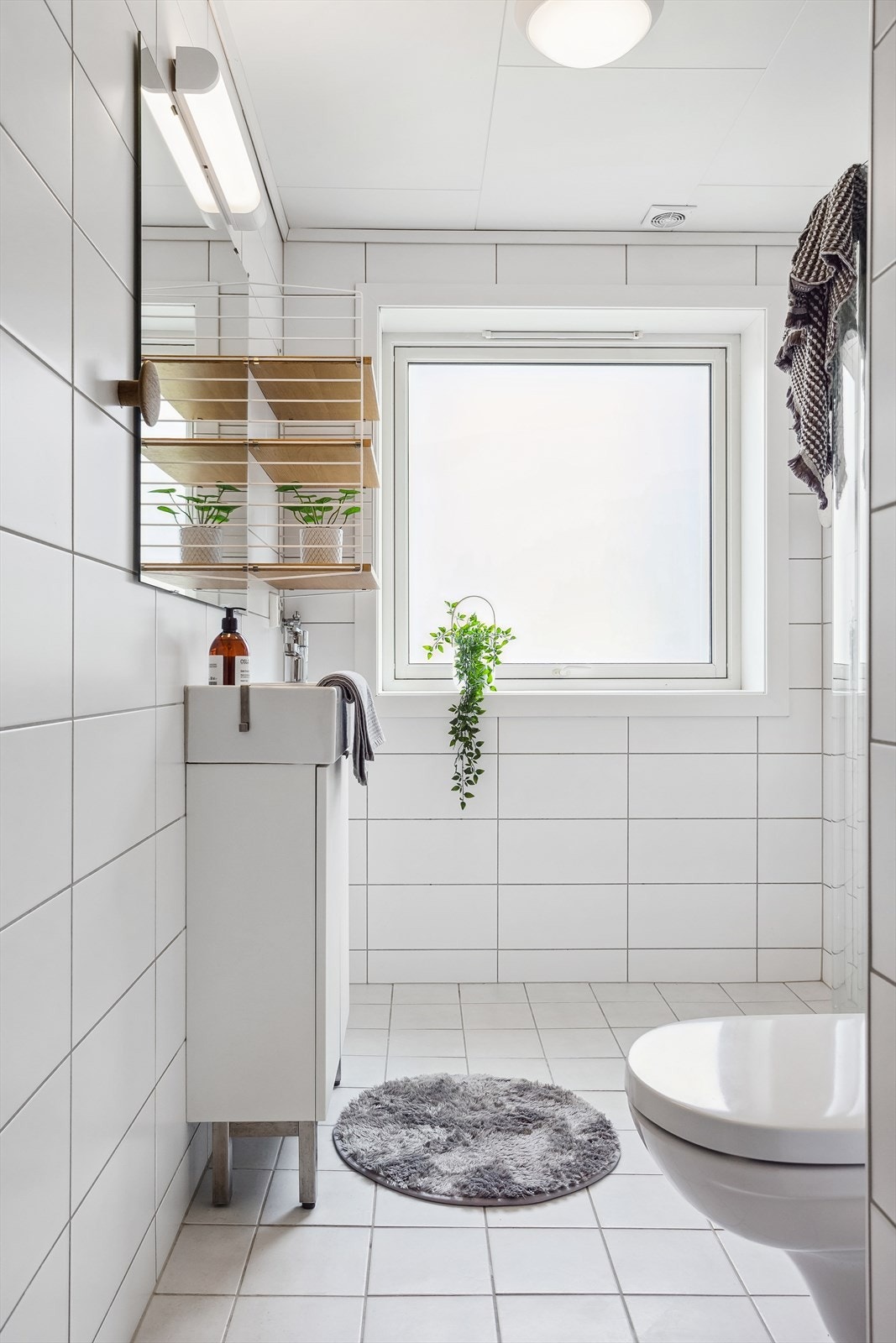 Badet er utstyrt med dusj, opplegg for vaskemaskin, servant med innredning og vegghengt toalett. Galleribilde