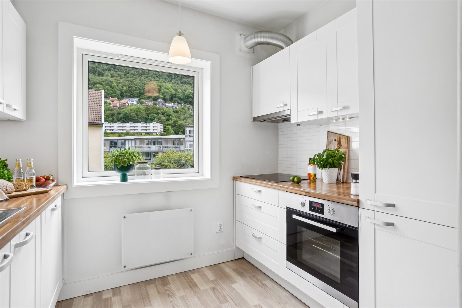 Kjøkkeninnredning med laminert benkeplate og profilerte hvite fronter. Galleribilde