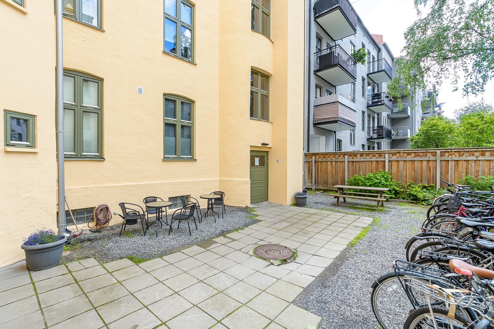 Opparbeidet gårdsrom med sykkelparkering, hellebelagte områder, sittegrupper og diverse beplantning. Galleribilde