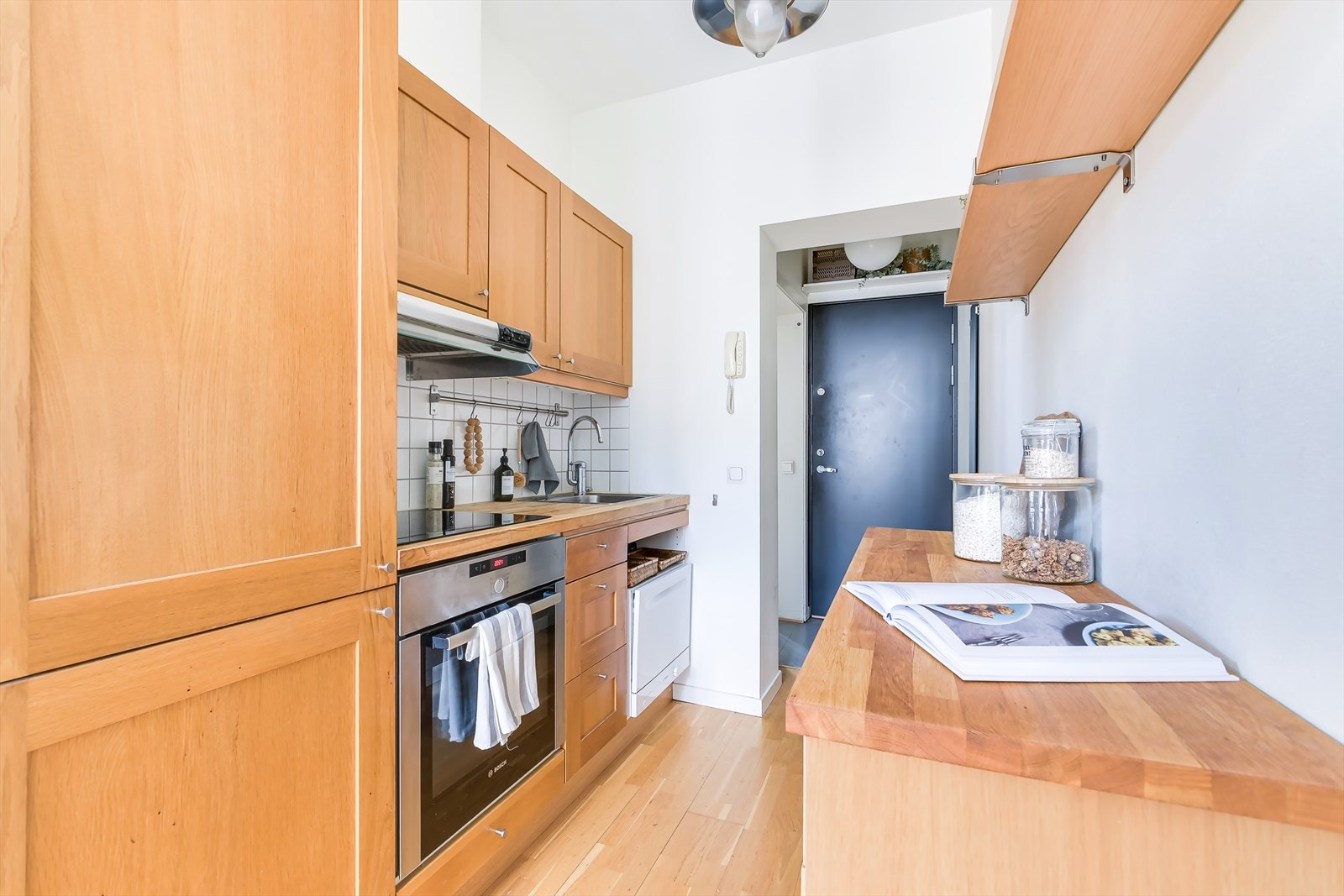 Kjøkkeninnredningen har ett-speilskap finerte skapfronter og en solid heltre benkeplate med fliser på bakvegg. Galleribilde