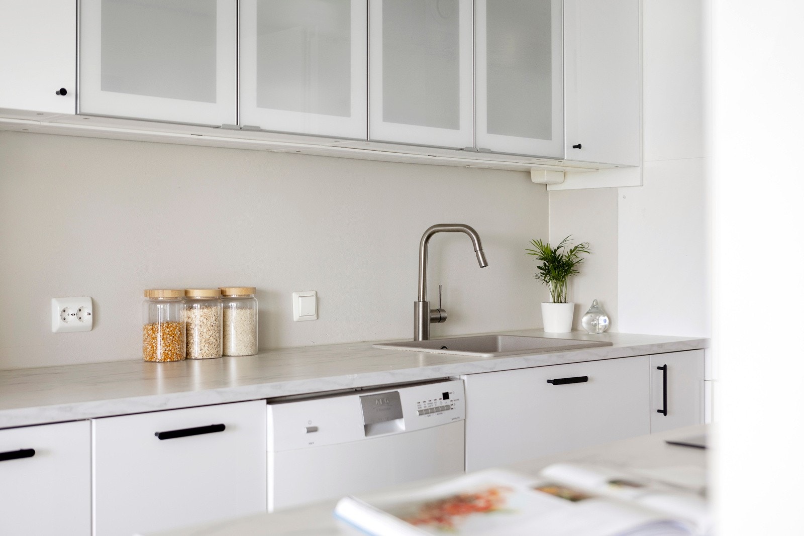 Hvite glatte fronter og en lekker benkeplate med matchende backsplash gir kjøkkenet et delikat preg Galleribilde