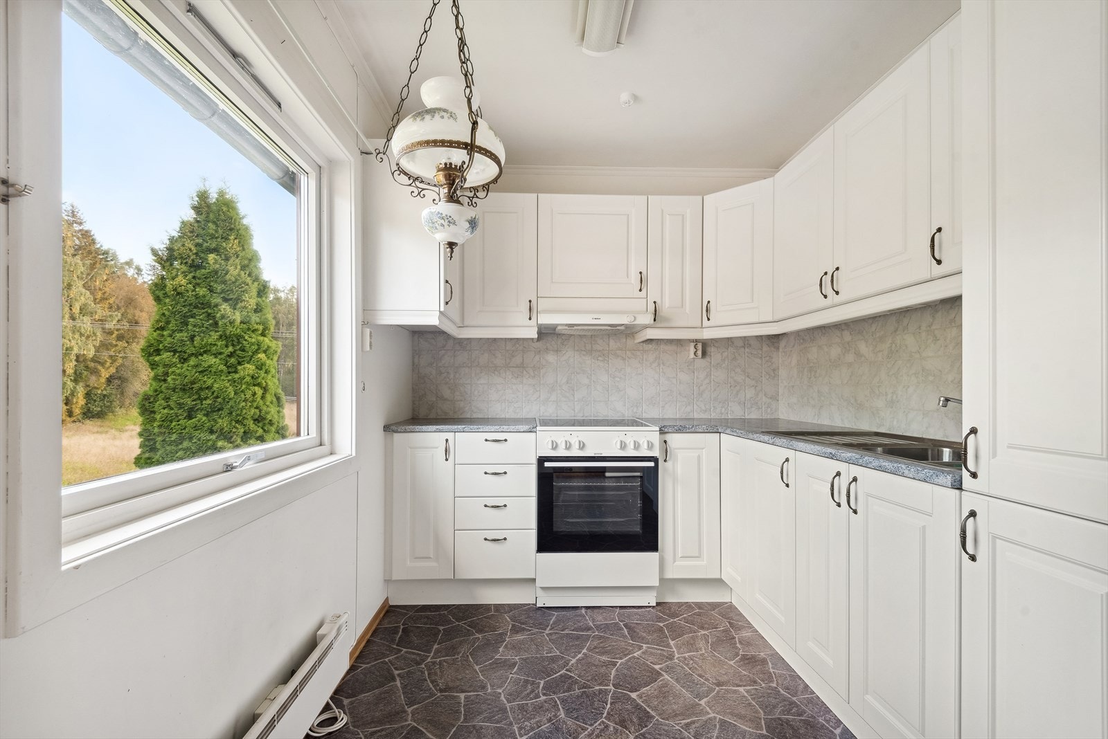 Separat kjøkken som vender mot baksiden av huset. Det har innredning i vinkel. Galleribilde