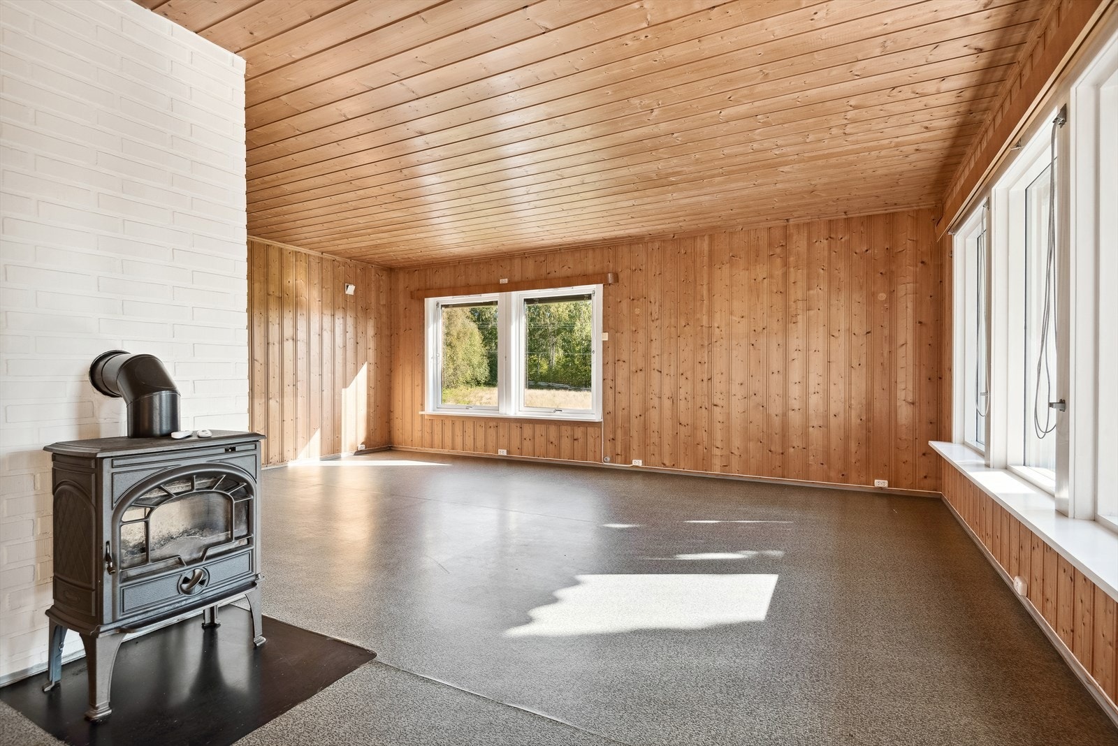 Romslig stue med vedovn av typen Jøtul. Galleribilde