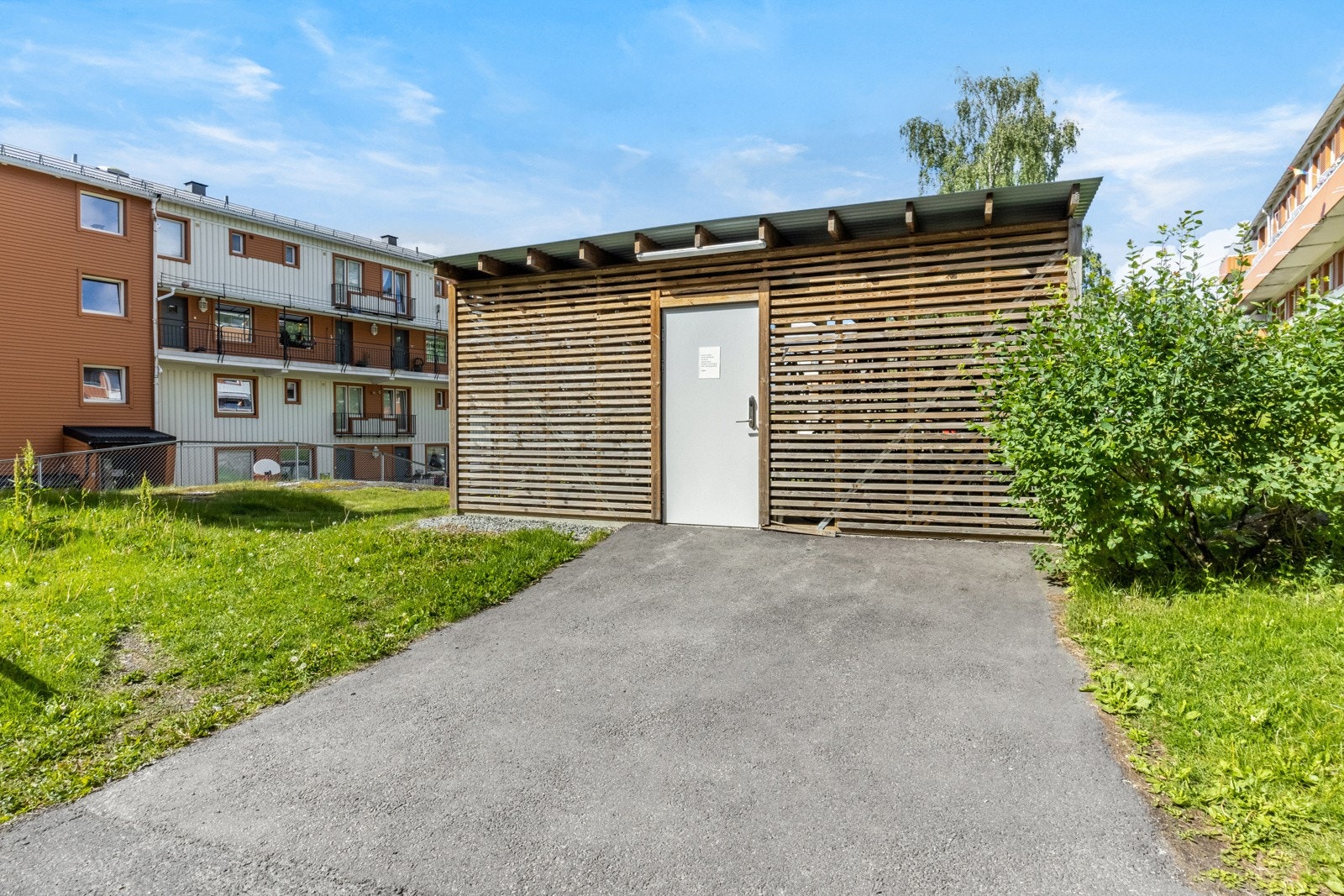 Moderne, låsbart sykkelskur er bygd på fellesområdet ved siden av blokken. Galleribilde