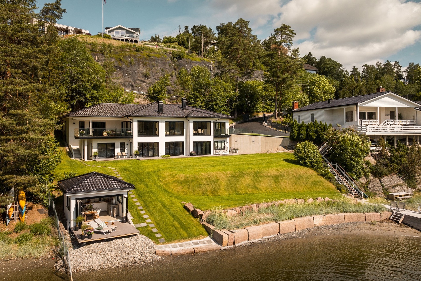 Vakker og stor tomt med plen, beplantning og strandlinje. Galleribilde