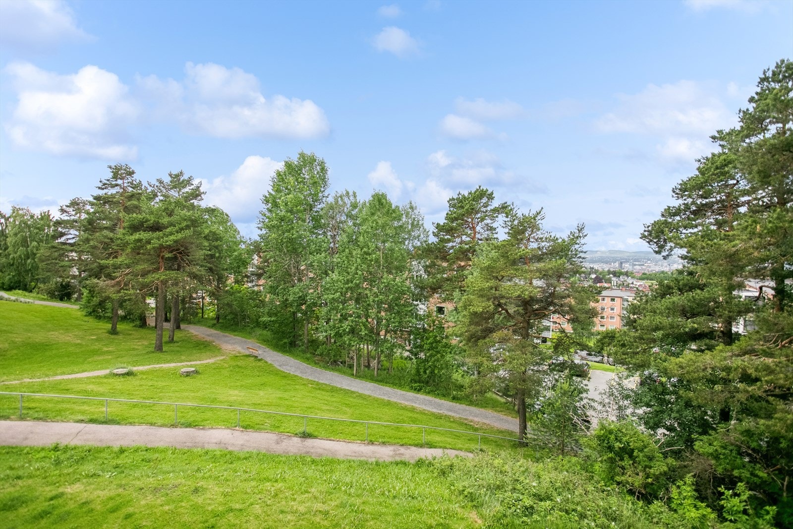 Pent opparbeidet felles tomt med plen, trær, beplanting, sittebenker, lekeplass og asfalterte internveier. Galleribilde